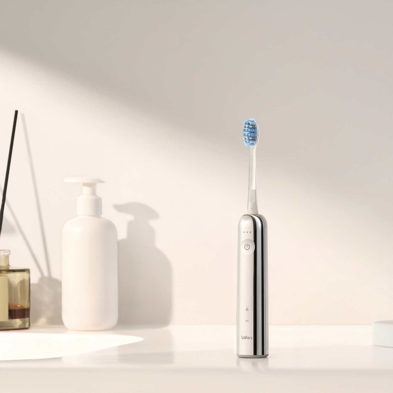 Brosse à dents électrique avec poils bleus, distributeur de savon et flacon de parfum.