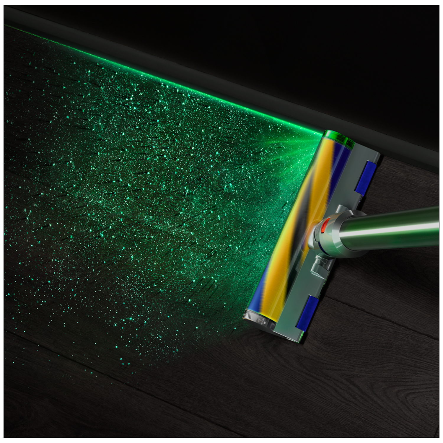 Een stofzuigerkop zendt groen laserlicht uit dat stofdeeltjes op een donkere vloer verlicht.