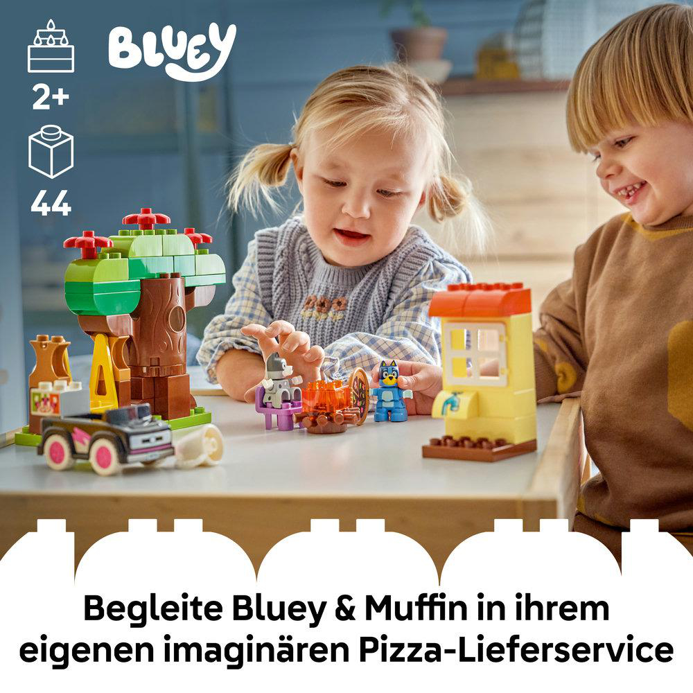Zwei Kinder spielen mit Bluey-Bauspielzeug, einem Baum, einem Auto und Figuren.
