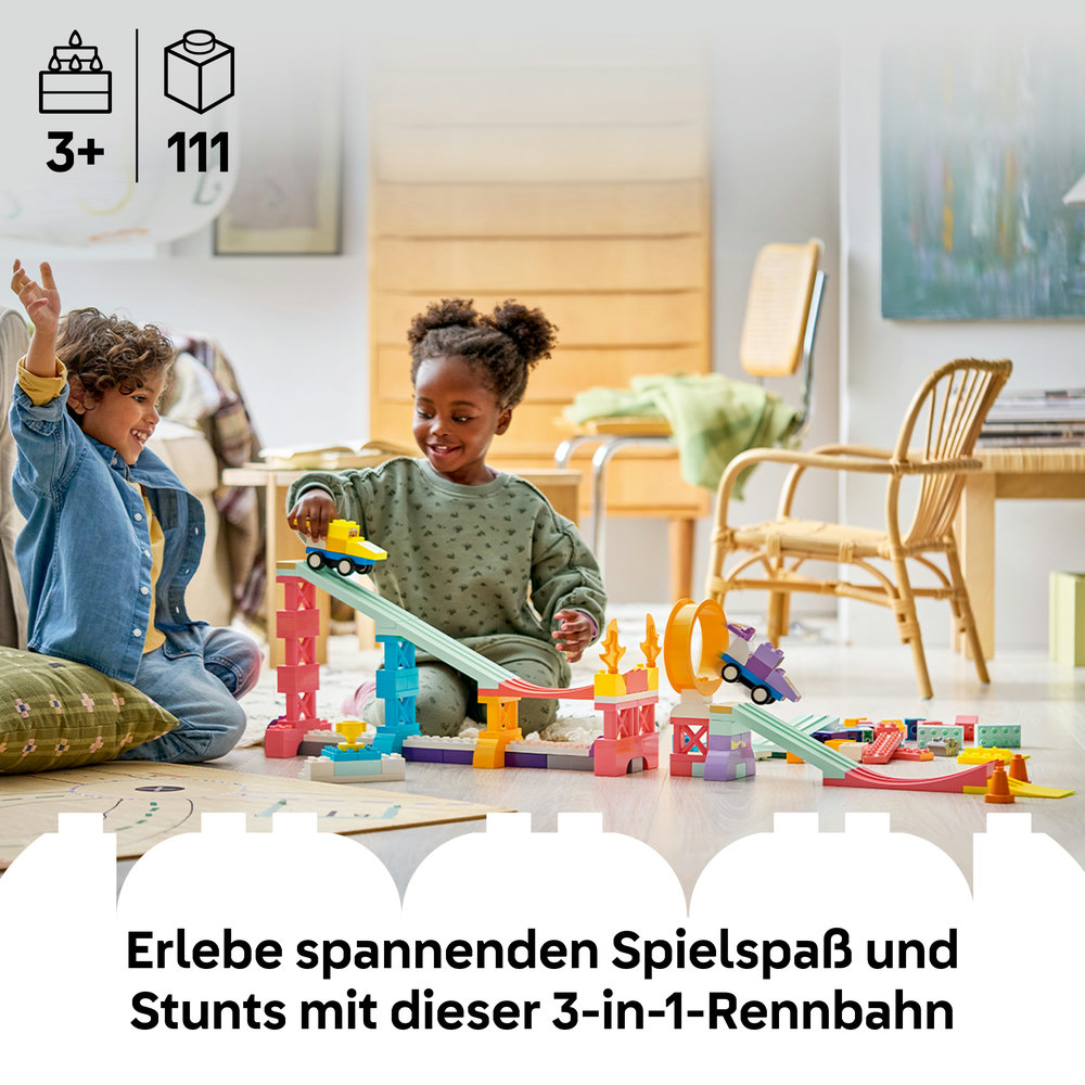Zwei Kinder bauen eine bunte Spielzeug-Rennbahn mit Autos und Bausteinen.