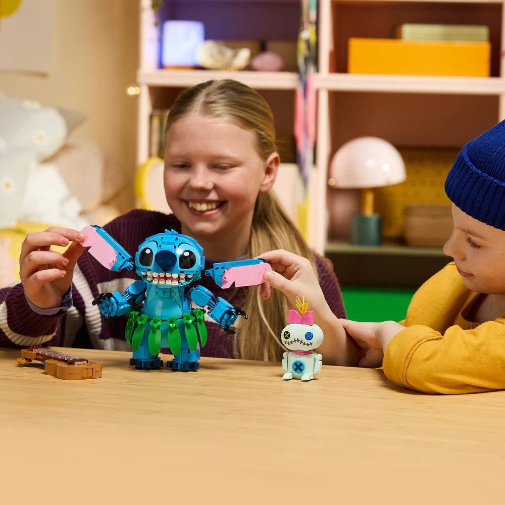 Mädchen und Junge spielen mit Stitch und Scrump Lego-Figuren auf einem Tisch.