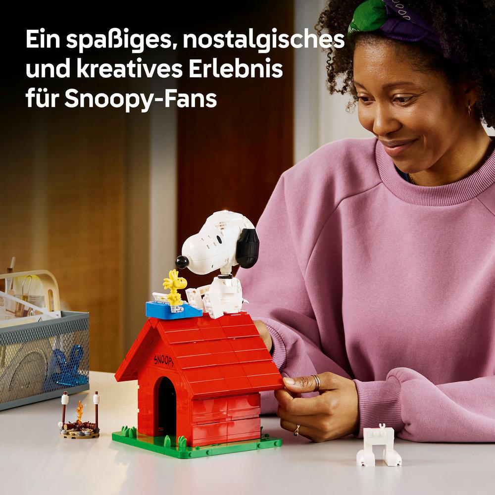 Eine Frau blickt auf ein Snoopy-Lego-Set mit seinem Hundehäuschen und Woodstock.