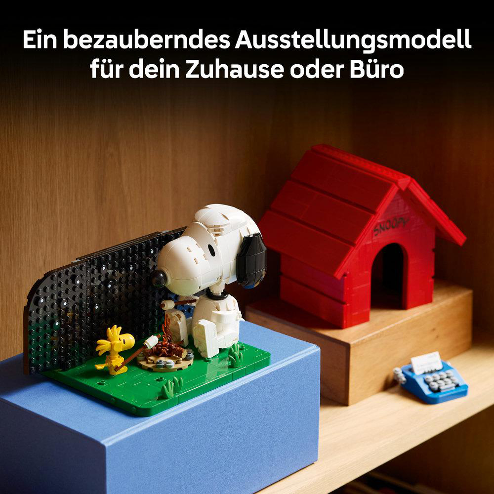 Snoopy-Modell mit Woodstock und Hundehütte aus Legosteinen auf einem blauen Sockel.