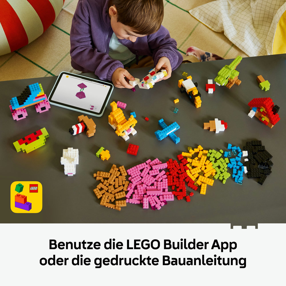 Junge baut Lego mit Tablet. Bunte Steine und Modelle auf Tisch.