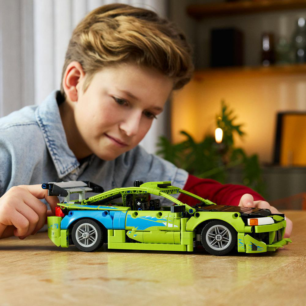 Ein Junge baut ein grünes und blaues Spielzeugauto mit Flügeln.