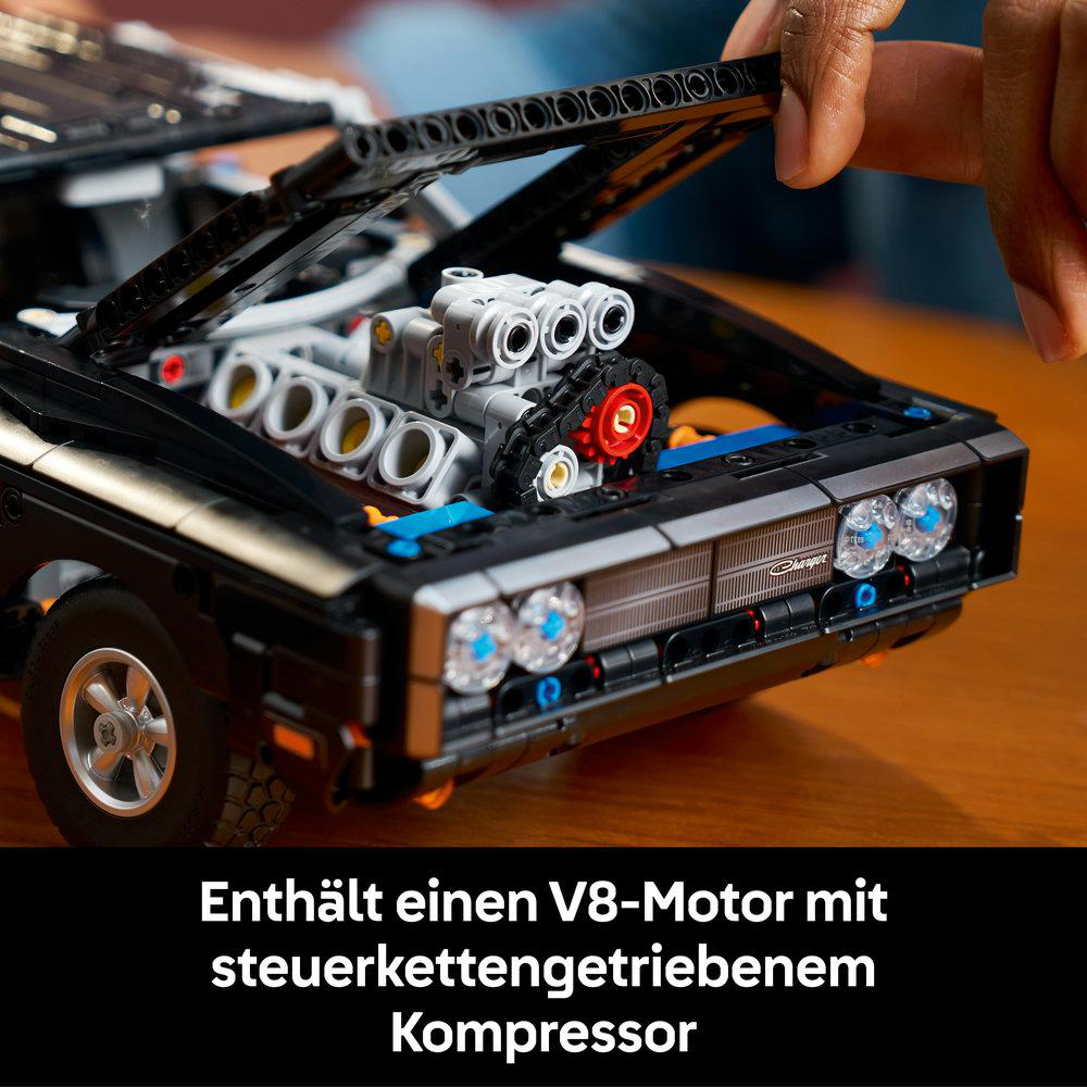 Schwarzer LEGO Automotor-Detail mit V8-Kolben, beweglicher Kette und rotem Lüfter.