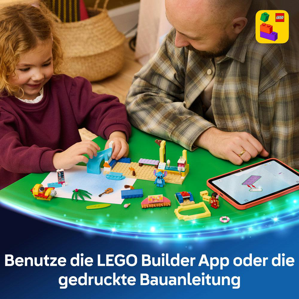 Mann und Kind bauen mit LEGO auf grünem Tisch, Tablet daneben.