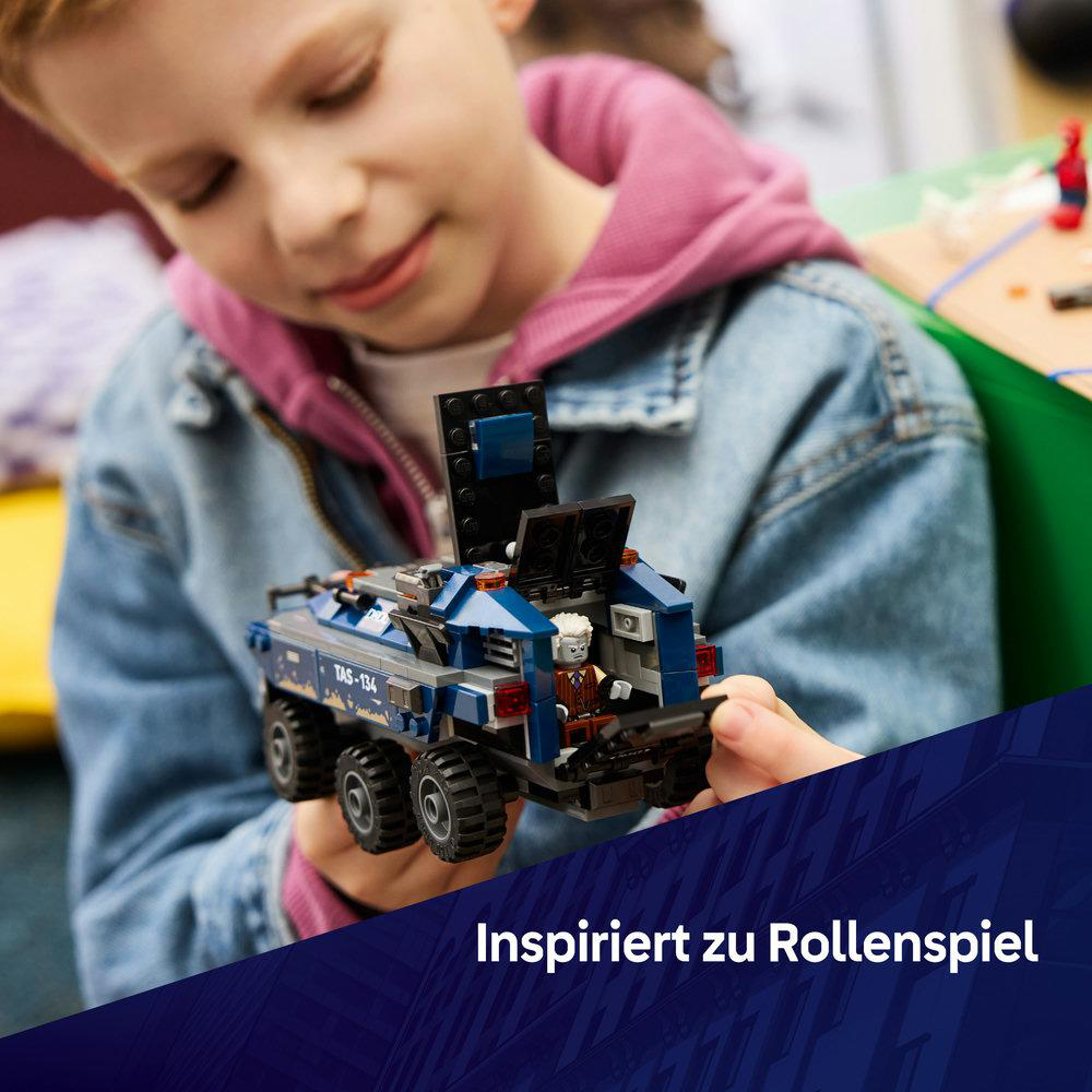 Ein Kind hält einen blauen und grauen Lego-LKW mit einer Minifigur darin. Der LKW hat sechs Räder.