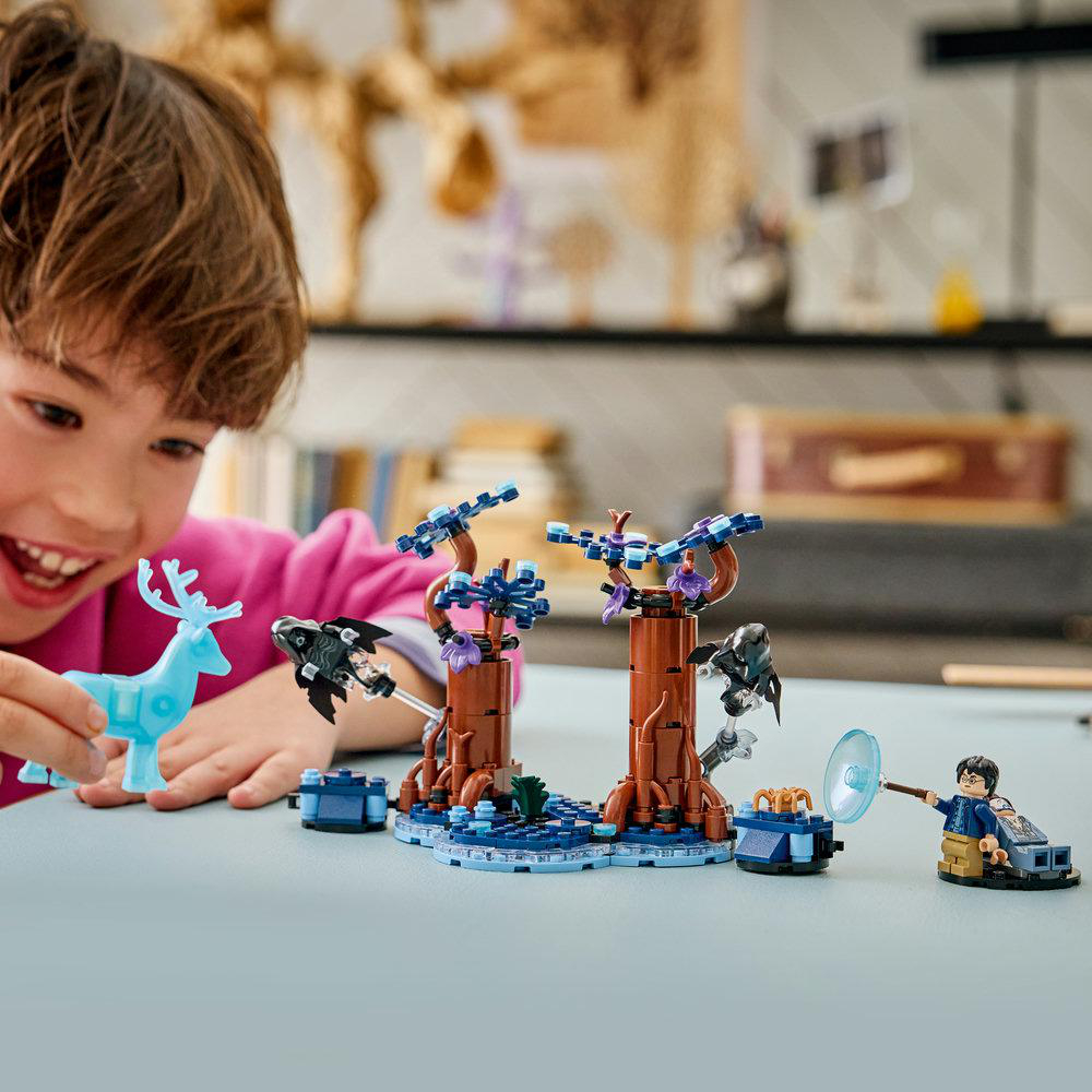 Junge spielt mit einem blauen Reh und LEGO-Set mit Bäumen und Figuren.