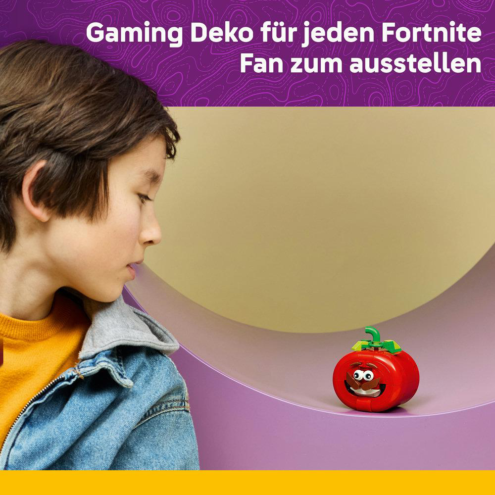 Ein Junge schaut auf eine rote Tomatenfigur mit Augen und einem Schnurrbart.
