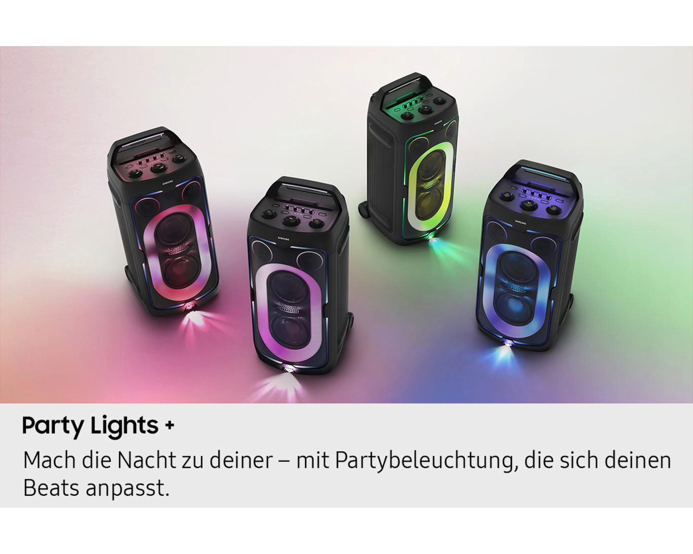 Vier schwarze Lautsprecher mit bunten Lichtern und Griffen auf grauem Hintergrund.