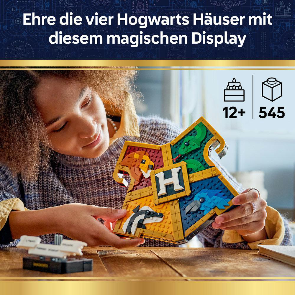 Eine Frau hält ein Hogwarts-Wappen mit vier Tierwappen und einem H.