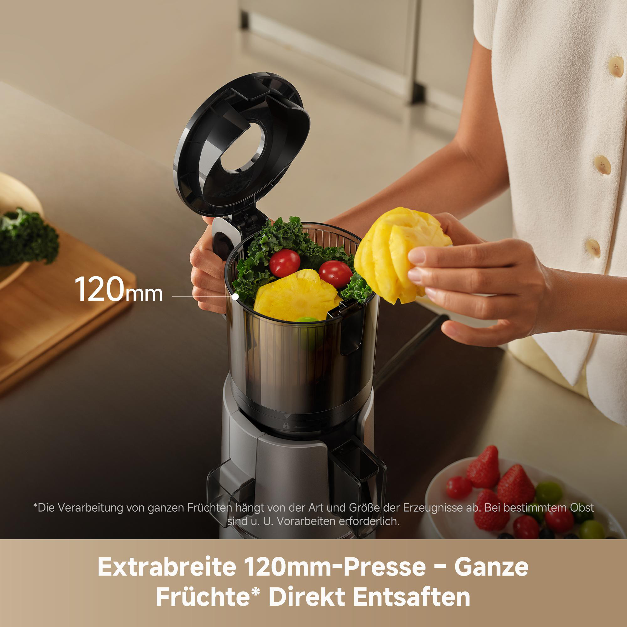 Eine Person gibt Ananas in eine Saftpresse mit Obst und Gemüse.