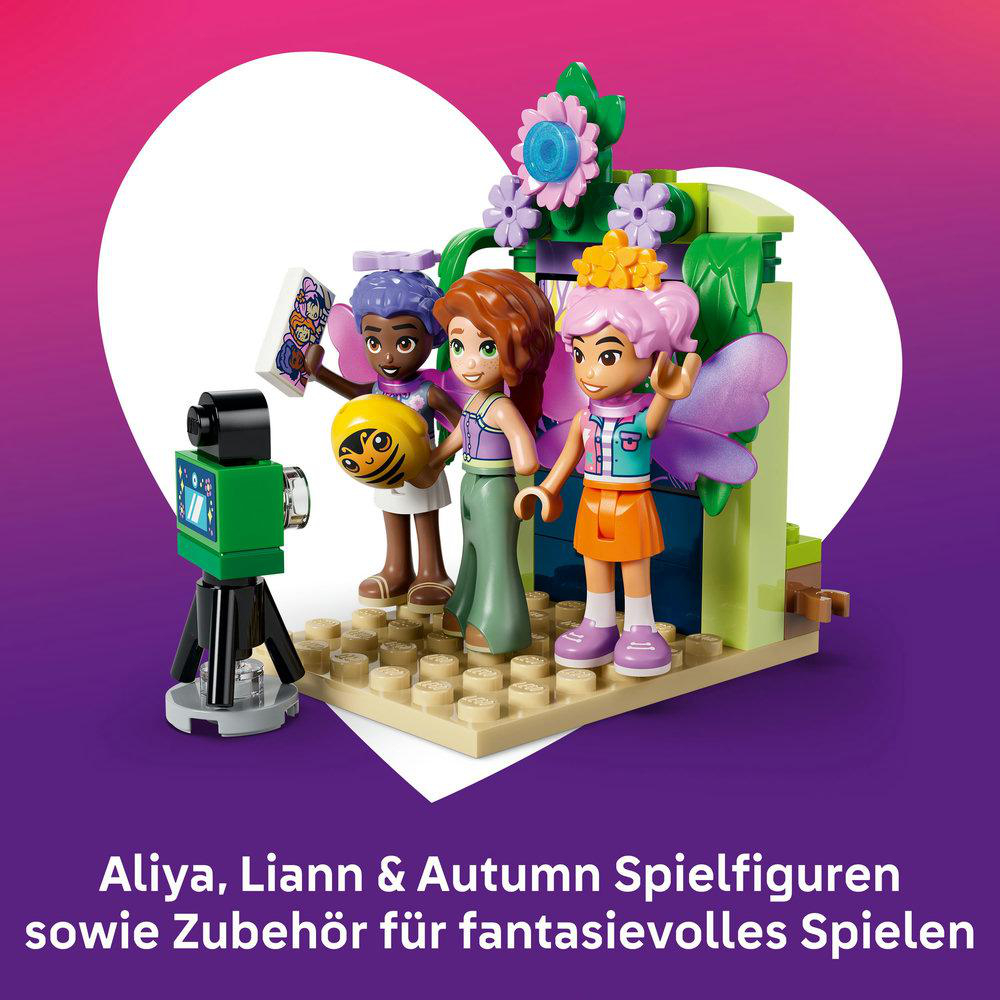 Drei Spielzeugfiguren stehen vor einer blumenbewachsenen Kulisse mit einer Kamera.