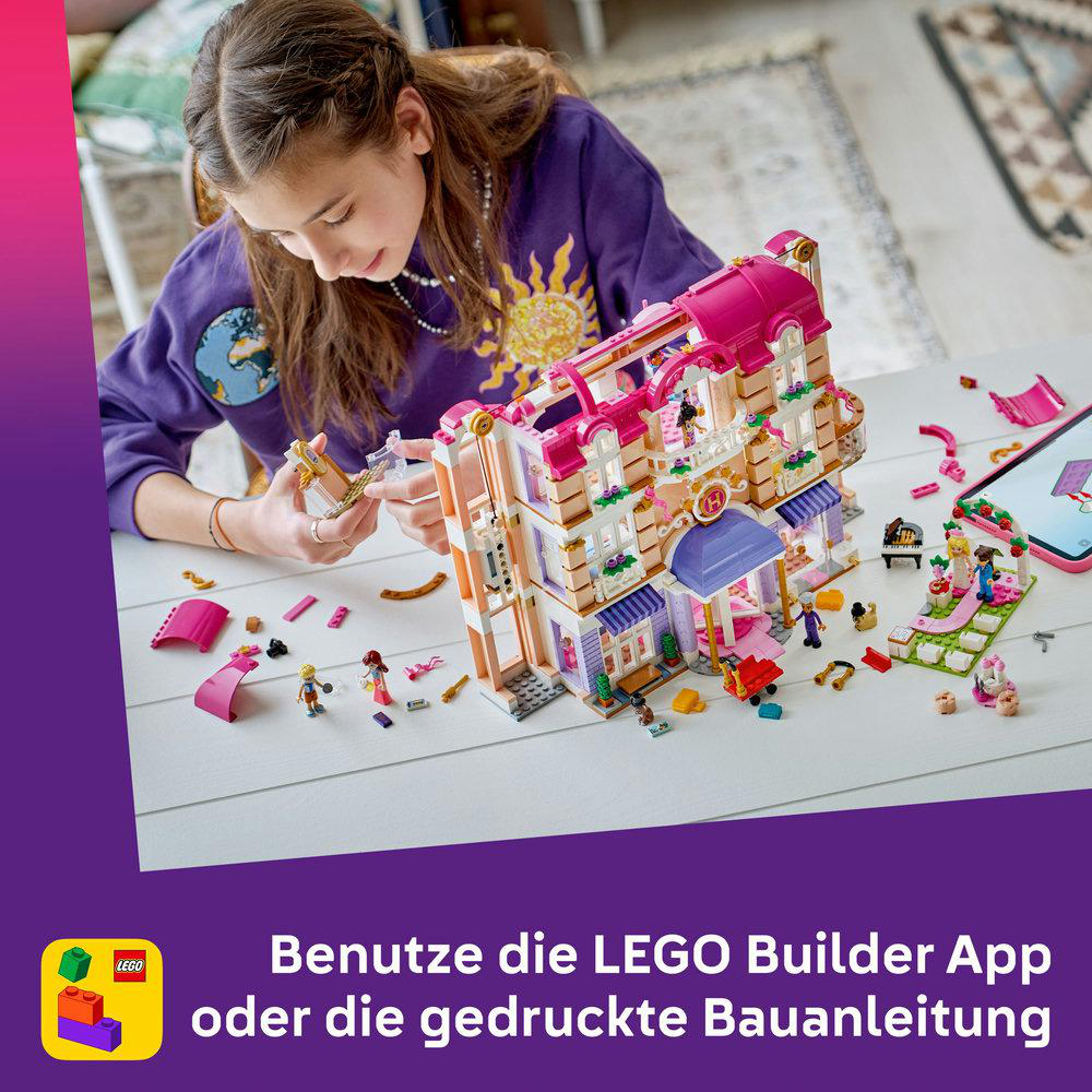 Ein Mädchen baut ein Lego-Gebäude mit Minifiguren und einem Tablet.