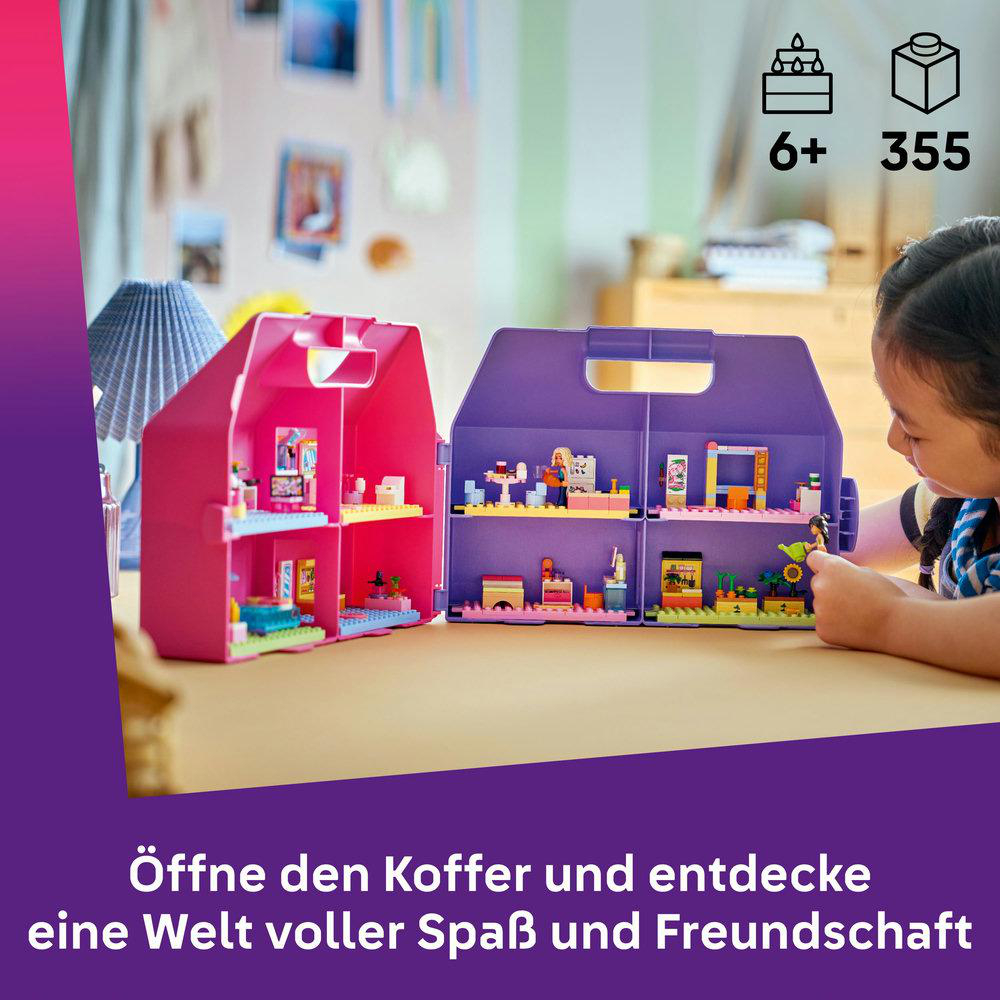 Ein Mädchen spielt mit einem aufklappbaren Spielzeugkoffer mit zwei Häusern.