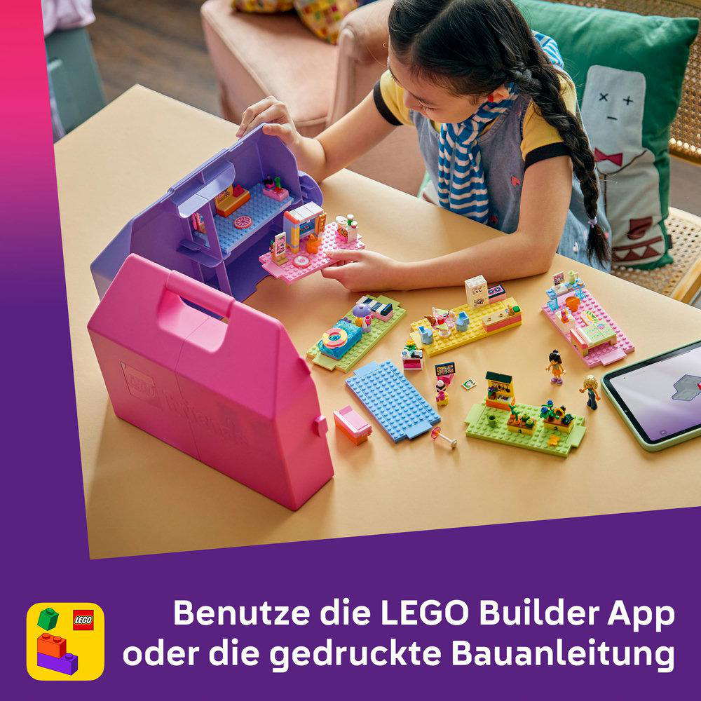 Ein Mädchen baut mit bunten LEGO-Teilen auf einem Tisch. Eine pinke und eine lila Kiste stehen vorne.