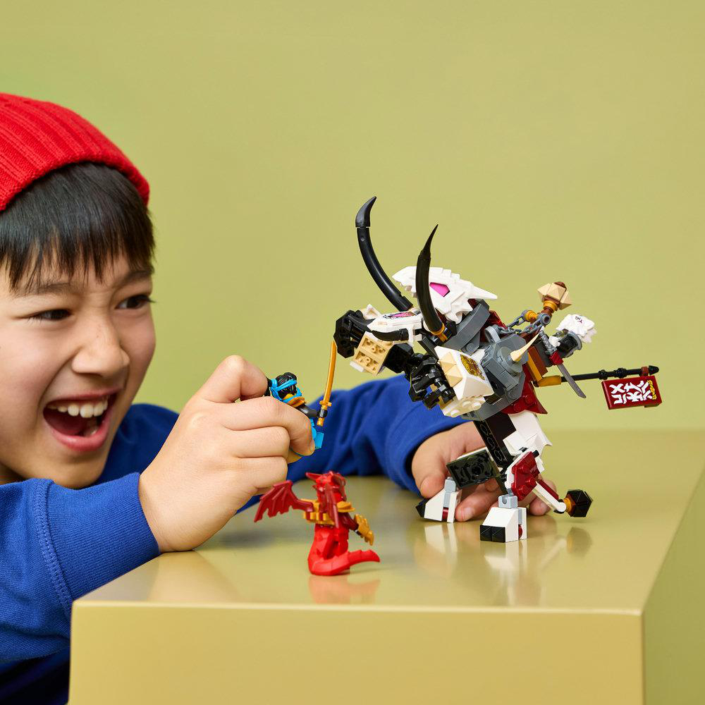 Ein Junge mit roter Mütze spielt mit Lego-Figuren und einem Drachen.