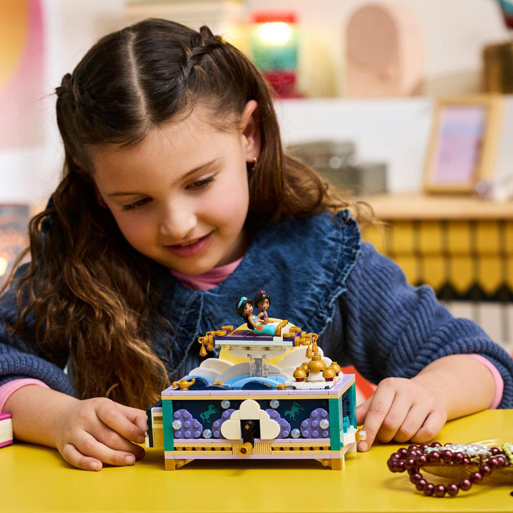 Ein Mädchen spielt mit einem bunten Lego-Drehkarussell mit Prinzessinnenfiguren.