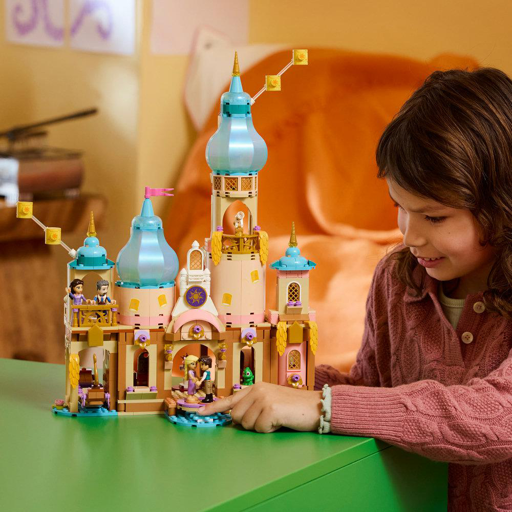 Ein Mädchen baut ein buntes Lego-Schloss mit Türmen und Figuren.