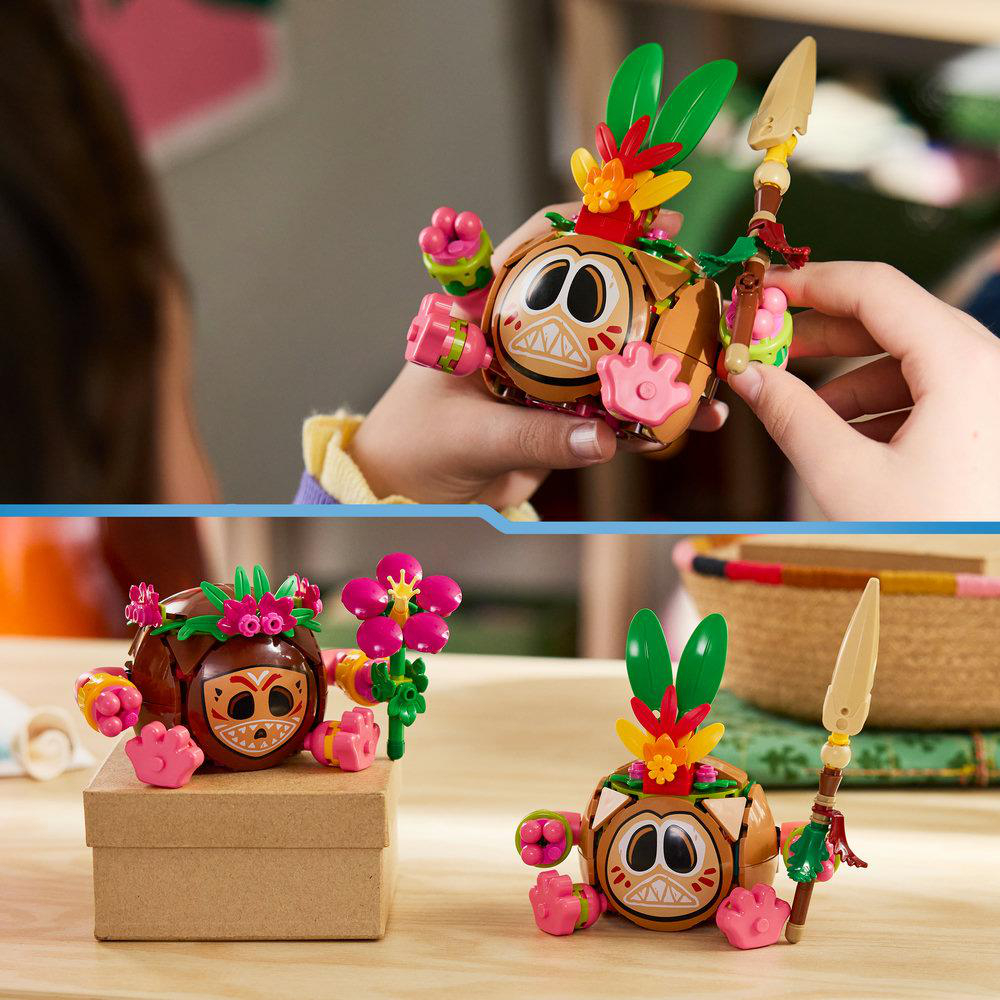 Zwei Spielzeugfiguren mit Kokosnusskörpern, Federn und Blumen, die auf einem Tisch stehen.