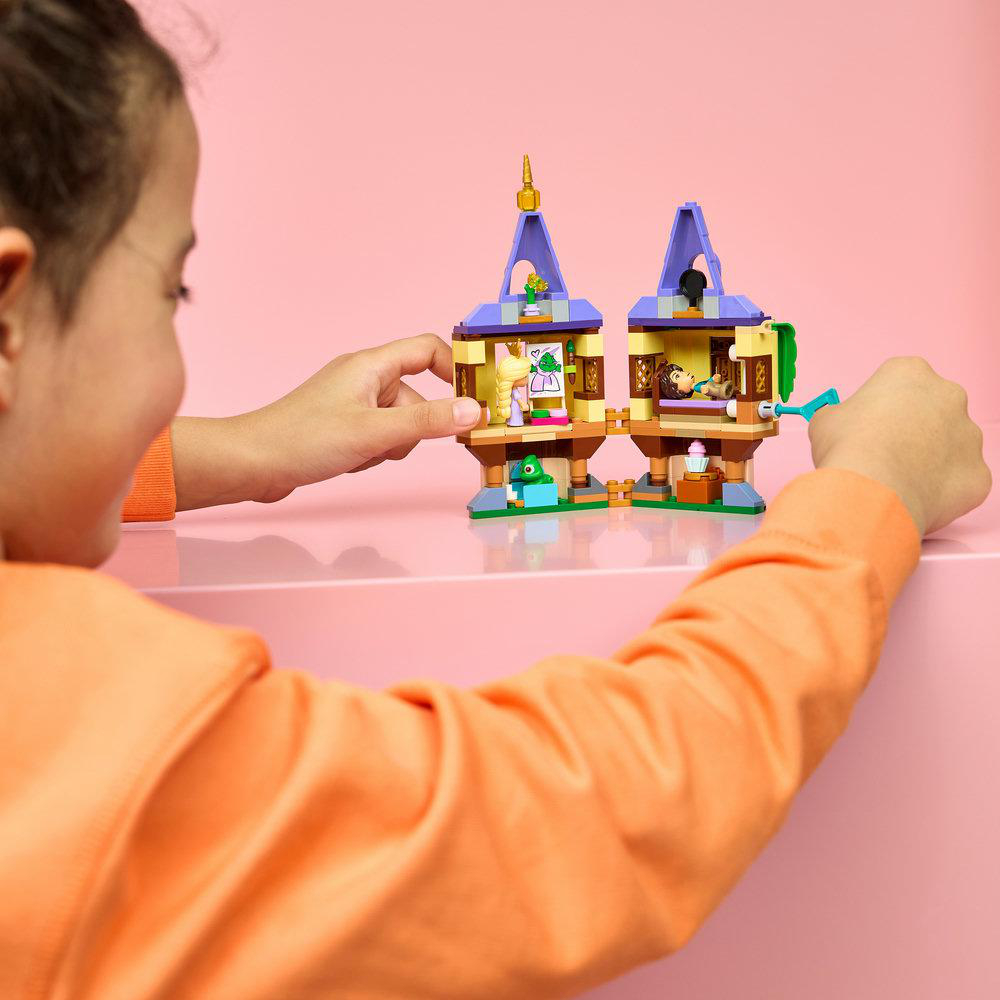 Kind spielt mit Lego-Turm, der eine Männchenfigur und ein Bett enthält.