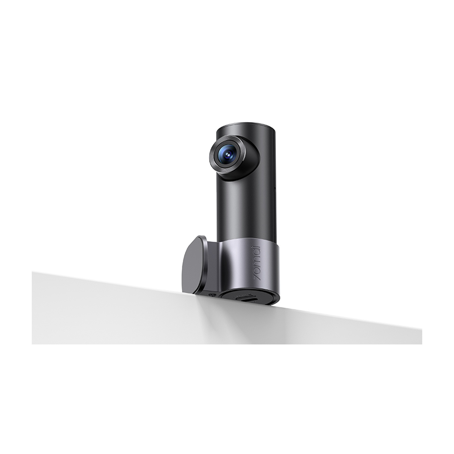 Una dashcam nera con anello argentato, montata su una superficie bianca.