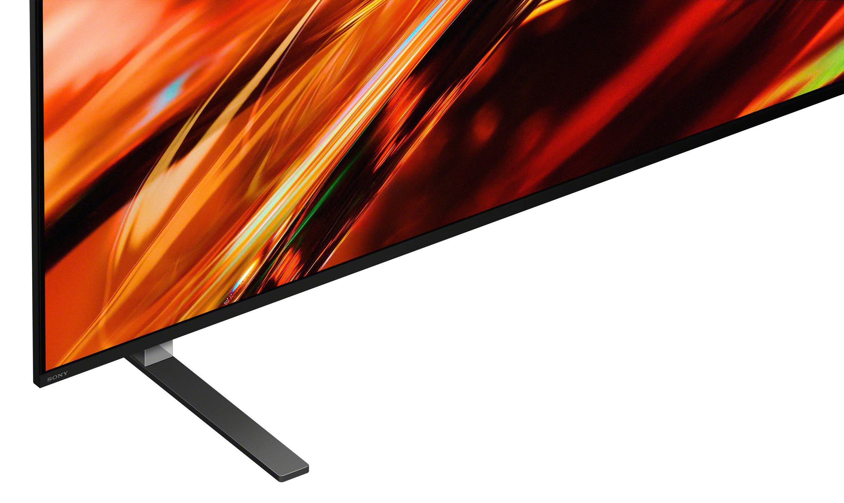 Telewizor Sony z abstrakcyjnym, pomarańczowo-czerwonym obrazem i czarnym stojakiem.