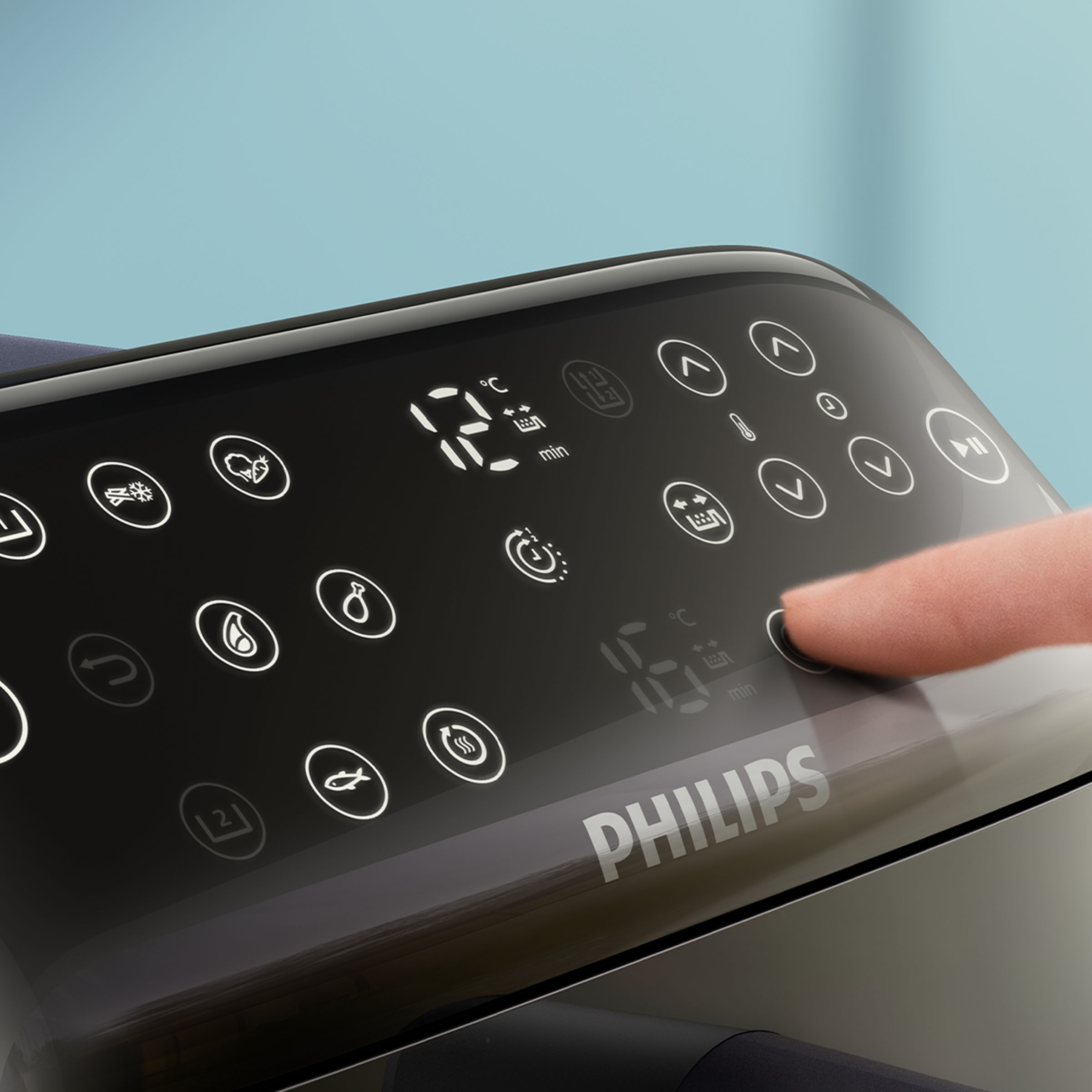 Palec naciska przycisk zasilania na panelu sterowania frytkownicy beztłuszczowej Philips z ikonami.