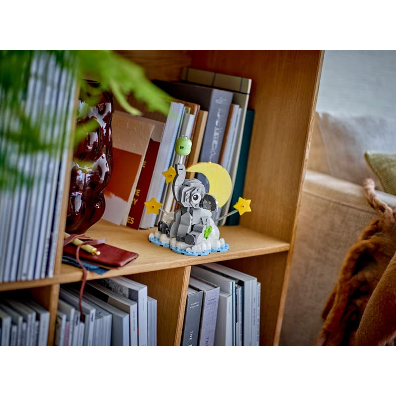 Een Lego-olifant zit op een plank met boeken, maan en sterren.