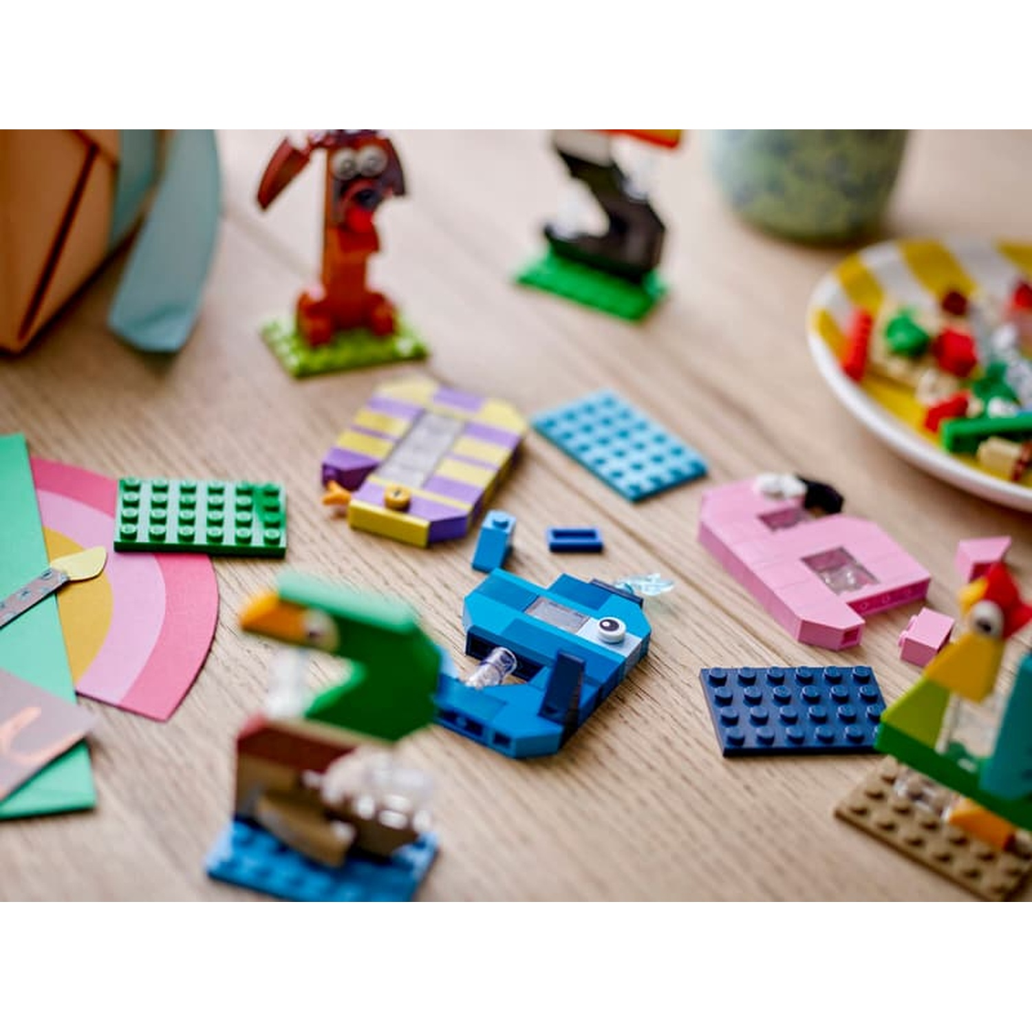 Créations colorées en LEGO : chien, poisson, poulet et autres formes sur une table en bois.