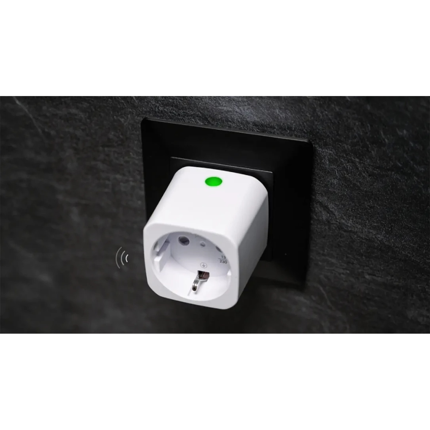 Una presa smart bianca con luce verde su muro di pietra nera.
