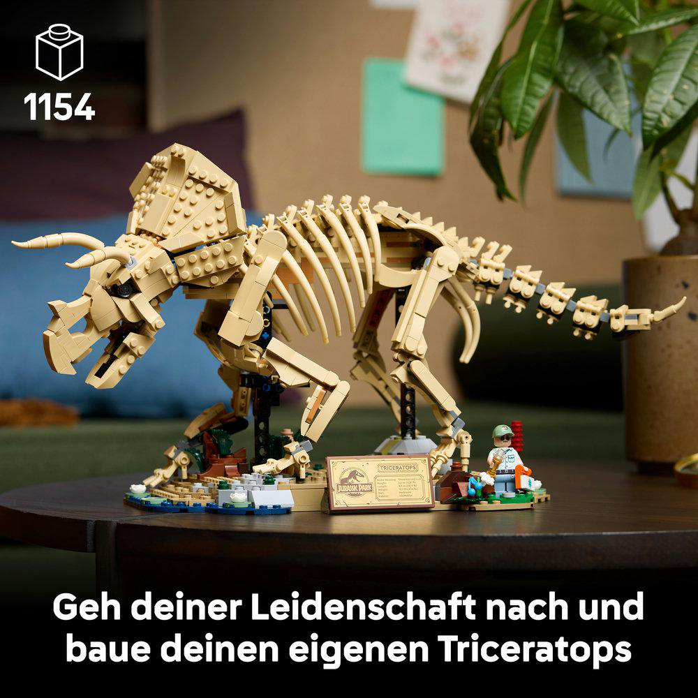 Ein Lego Triceratops Skelett auf einem Tisch, mit Minifigur und Jurassic Park Schild.