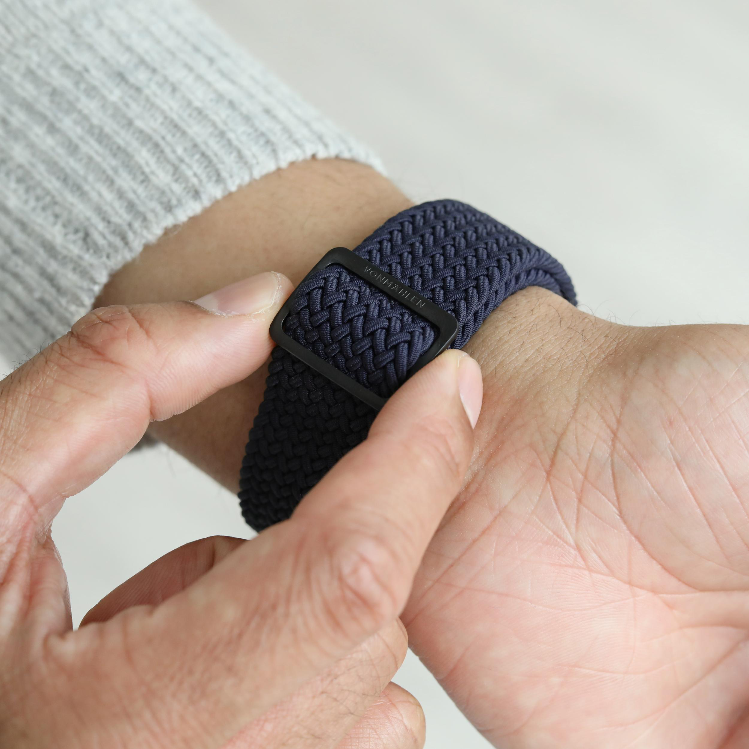 Dunkelblaues gewebtes Armband mit schwarzer Schnalle wird an einem Arm befestigt.