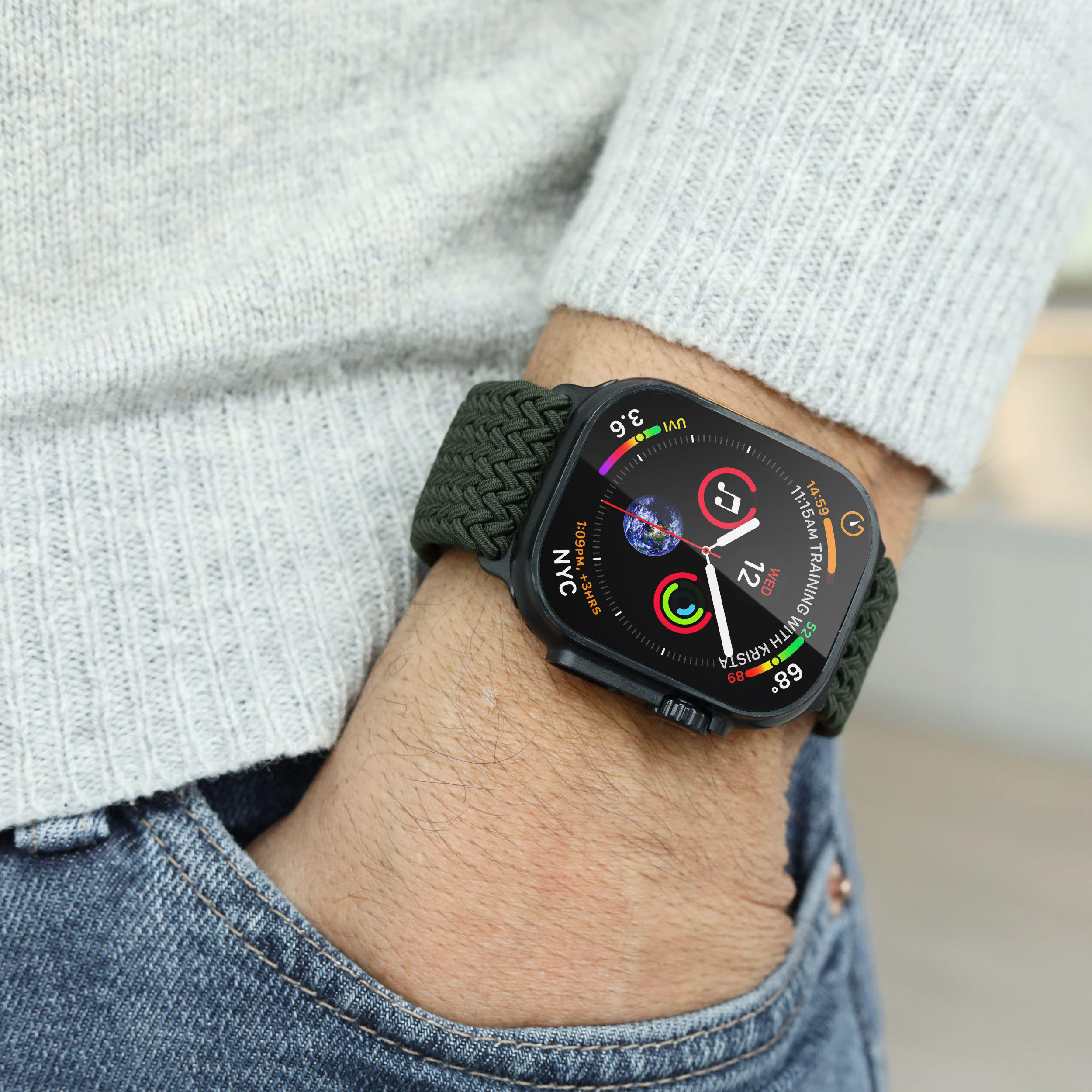 Grauer Pullover, Jeans und eine Smartwatch mit grünem Band. Angezeigte Infos: Zeit, UVI, Training.