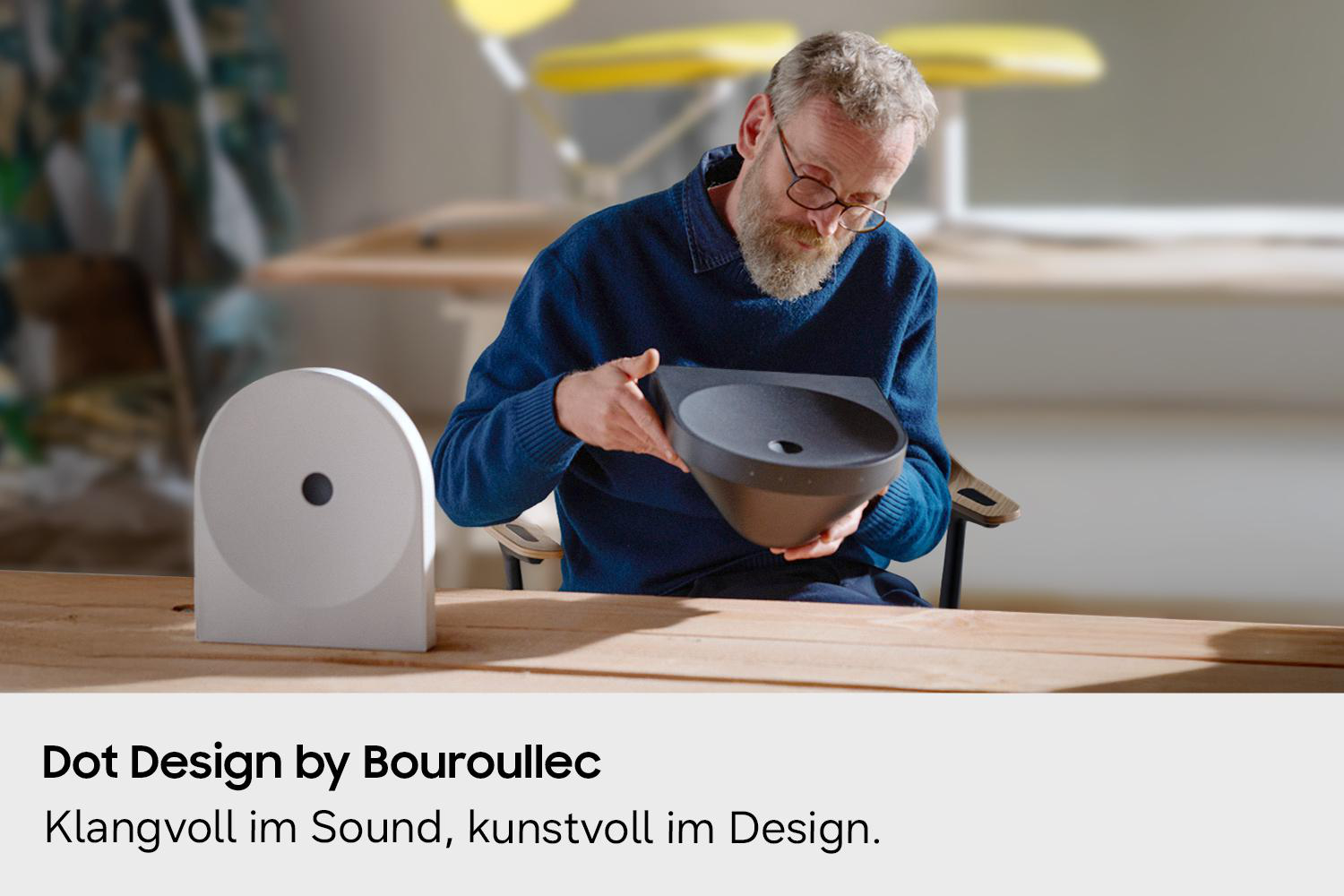 Mann mit Brille hält schwarzes Designobjekt; weißes Objekt links.