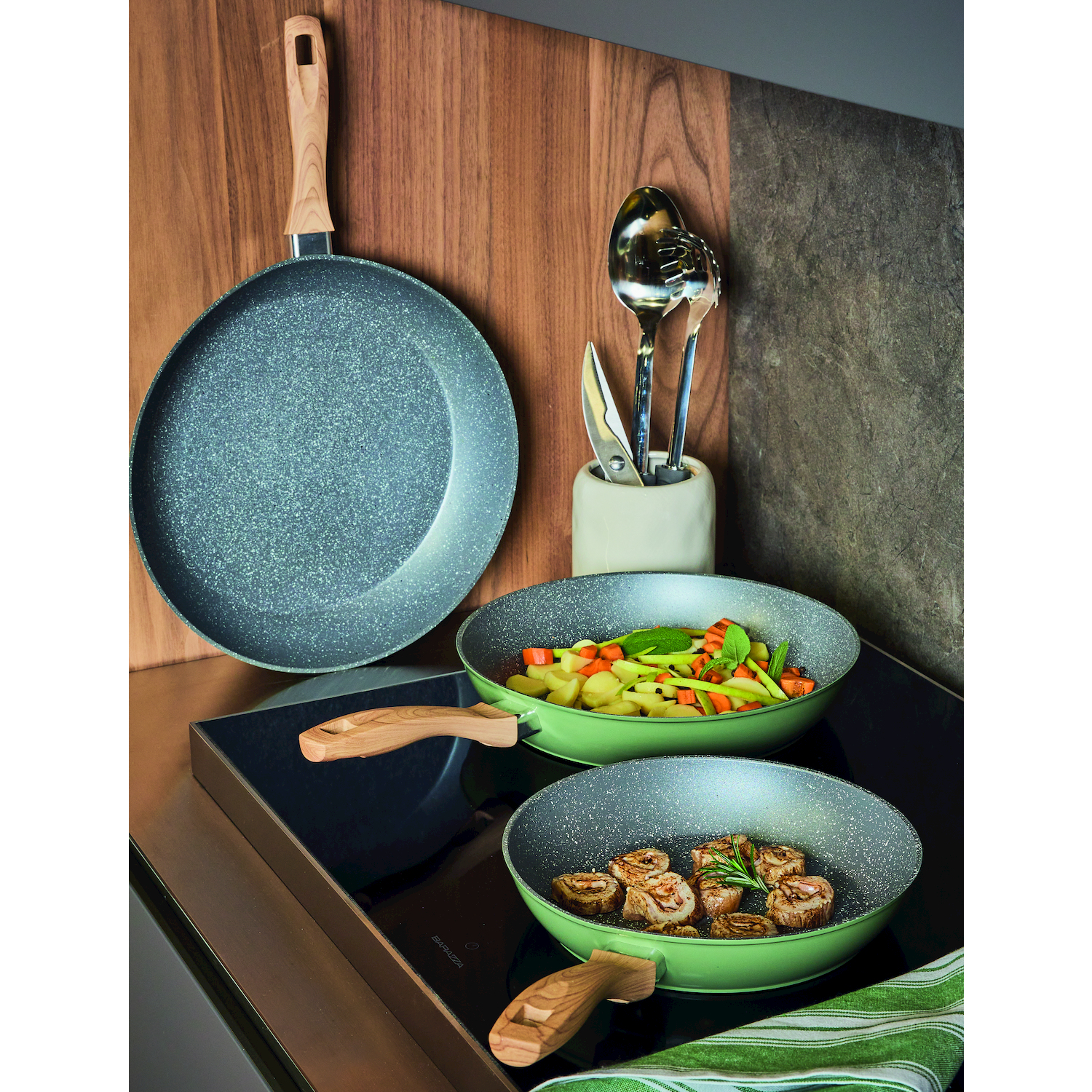 Utensili da cucina: due padelle, una con carne, una con verdure, e utensili da cucina.