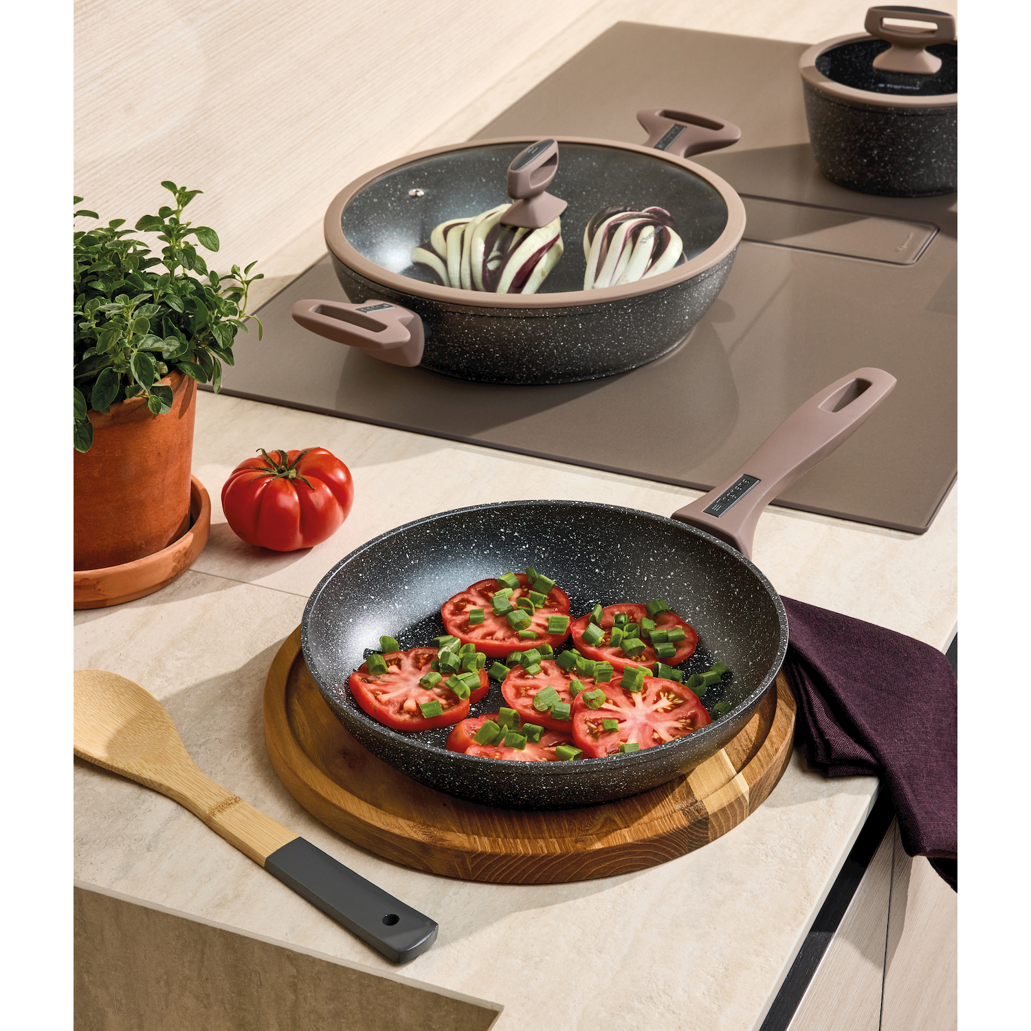 Una padella con pomodori a fette e cipollotti su un tagliere di legno.