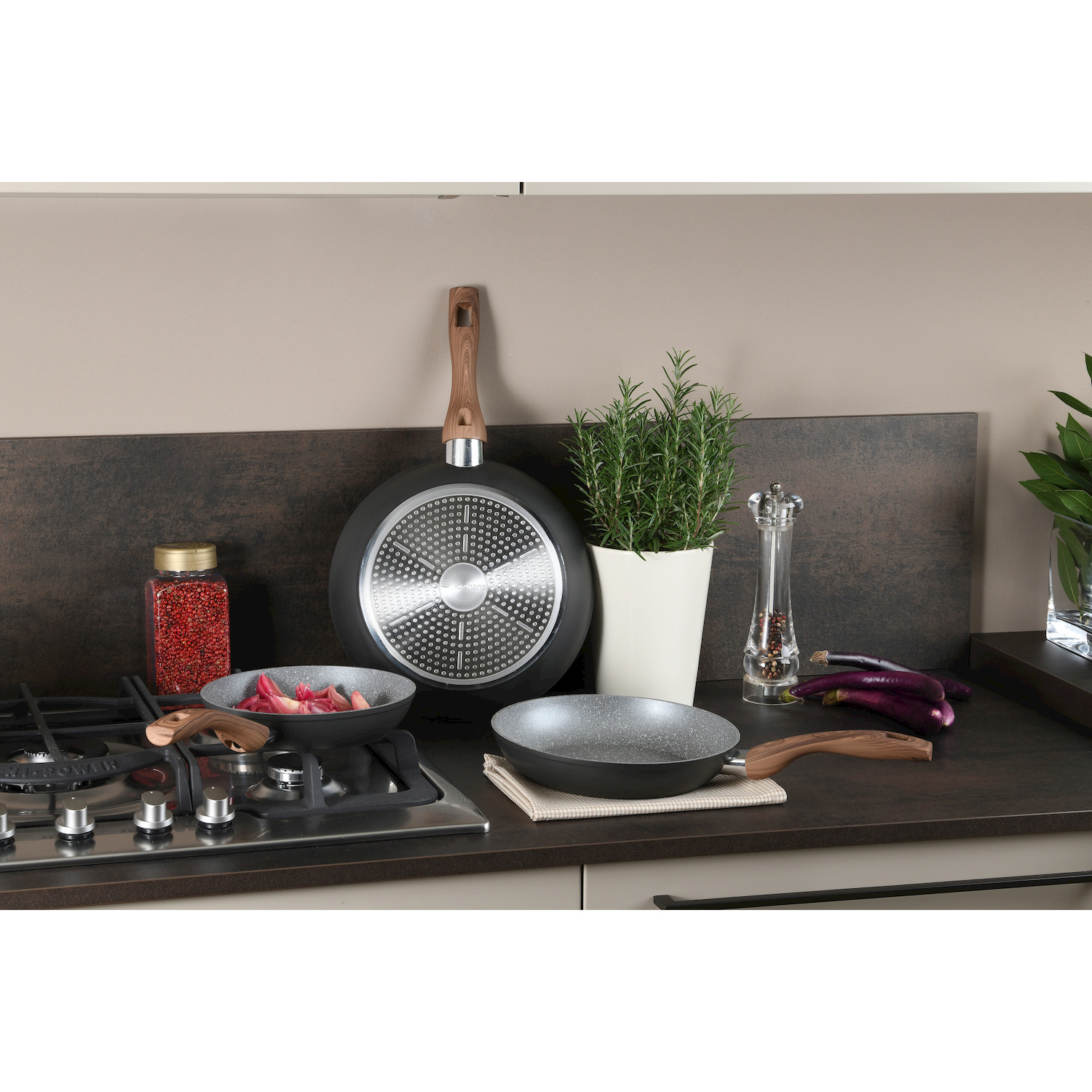Una scena di cucina con pentole, comprese padelle su un fornello a gas, melanzane e spezie.
