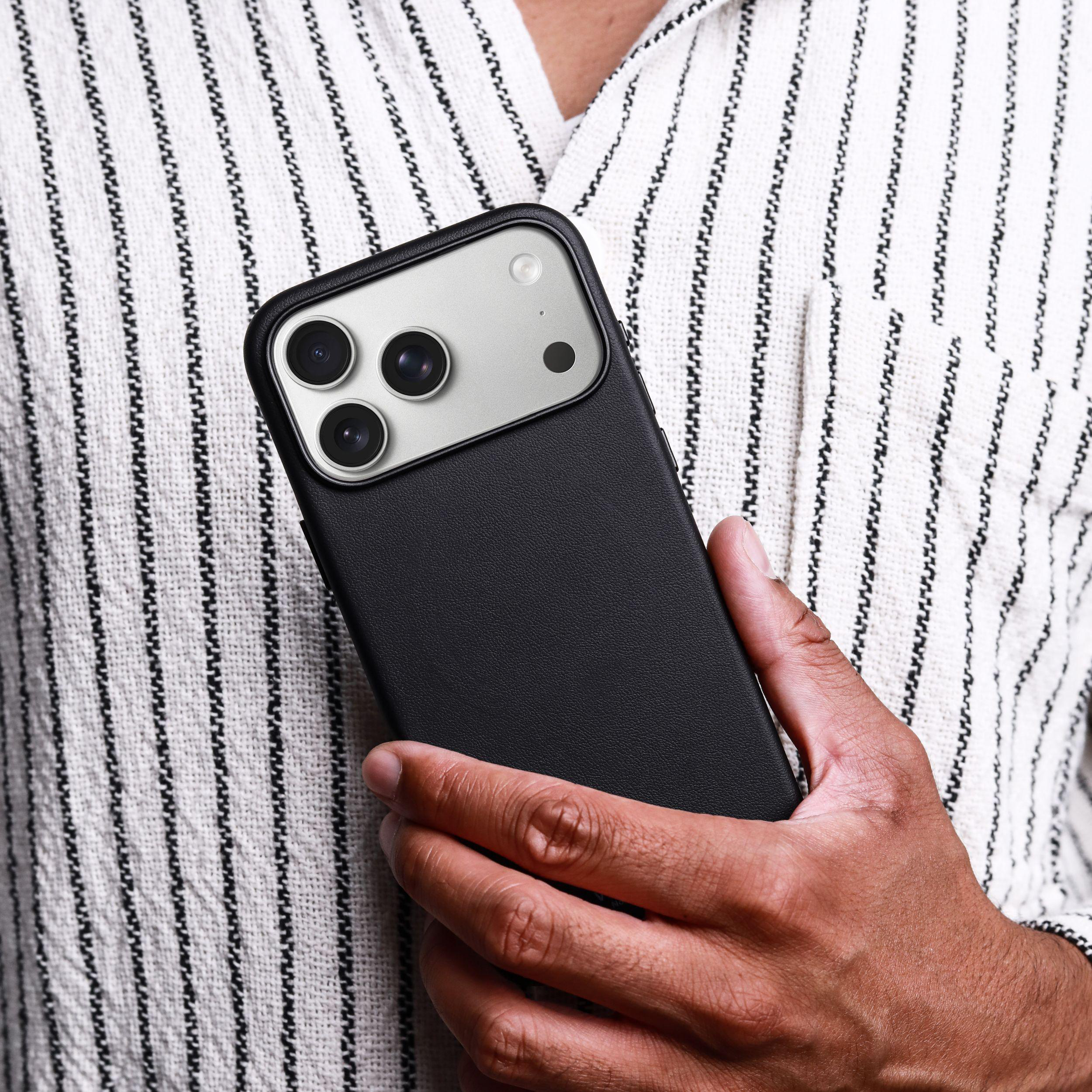 Ein Mann hält ein schwarzes Smartphone mit drei Kameras in der Hand.