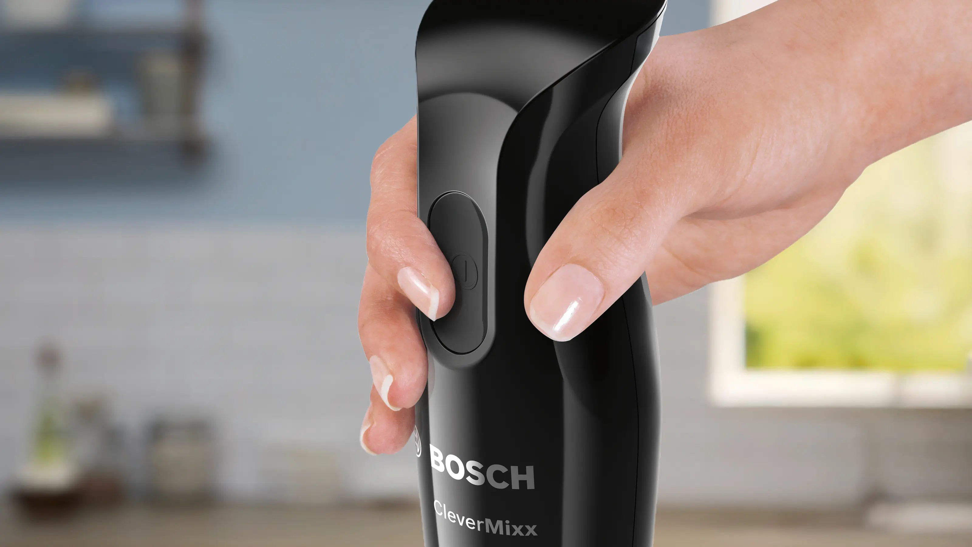 Egy kéz egy fekete, ezüst logós Bosch botmixert tart.