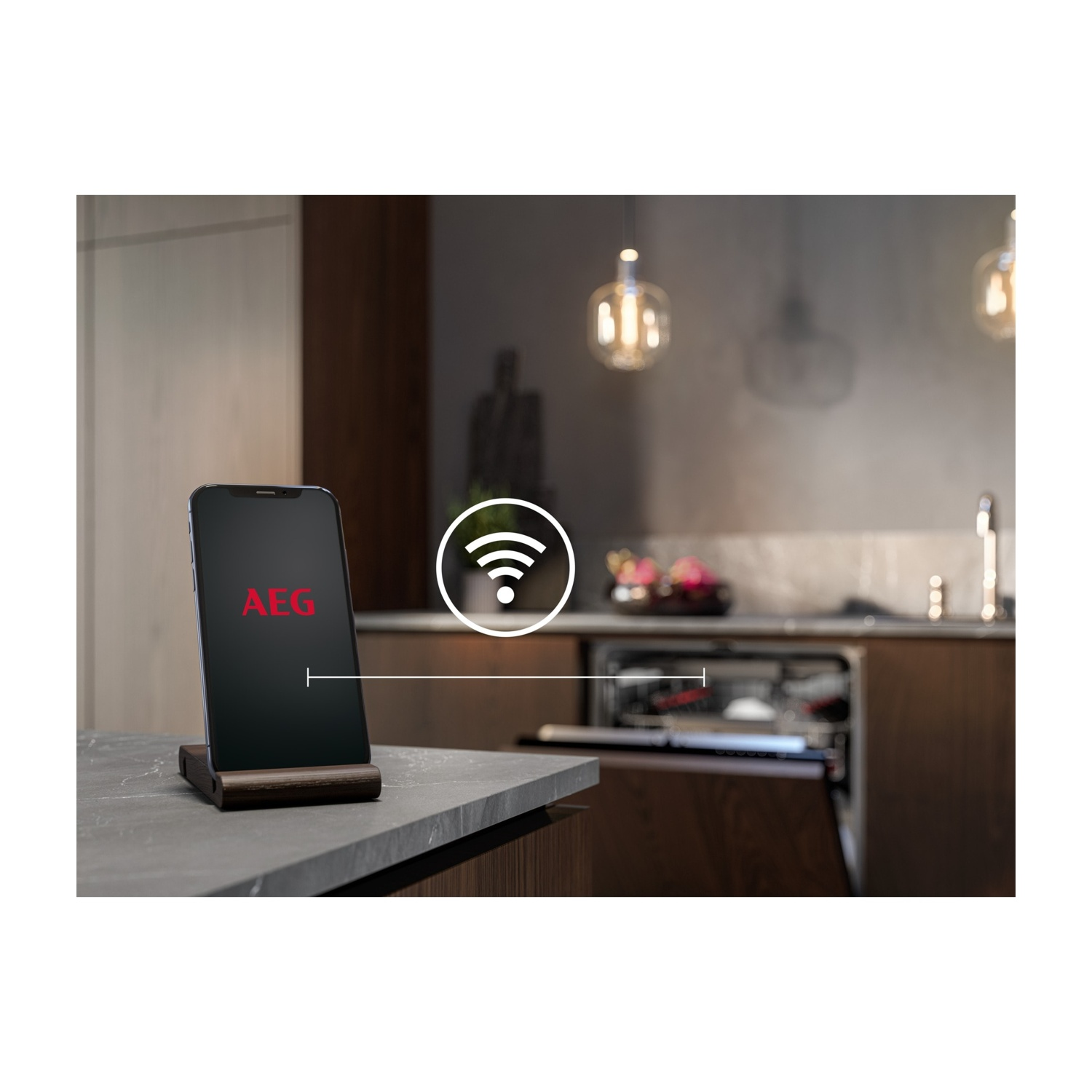 Uno smartphone con logo AEG è su un tavolo davanti a una lavastoviglie.