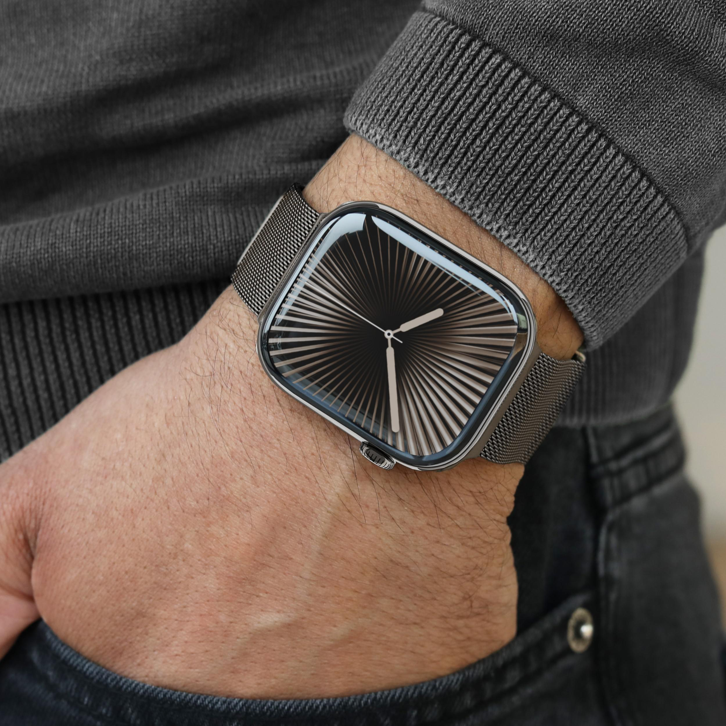 Eine Person trägt eine graue Strickjacke und eine Uhr mit schwarzem Zifferblatt.
