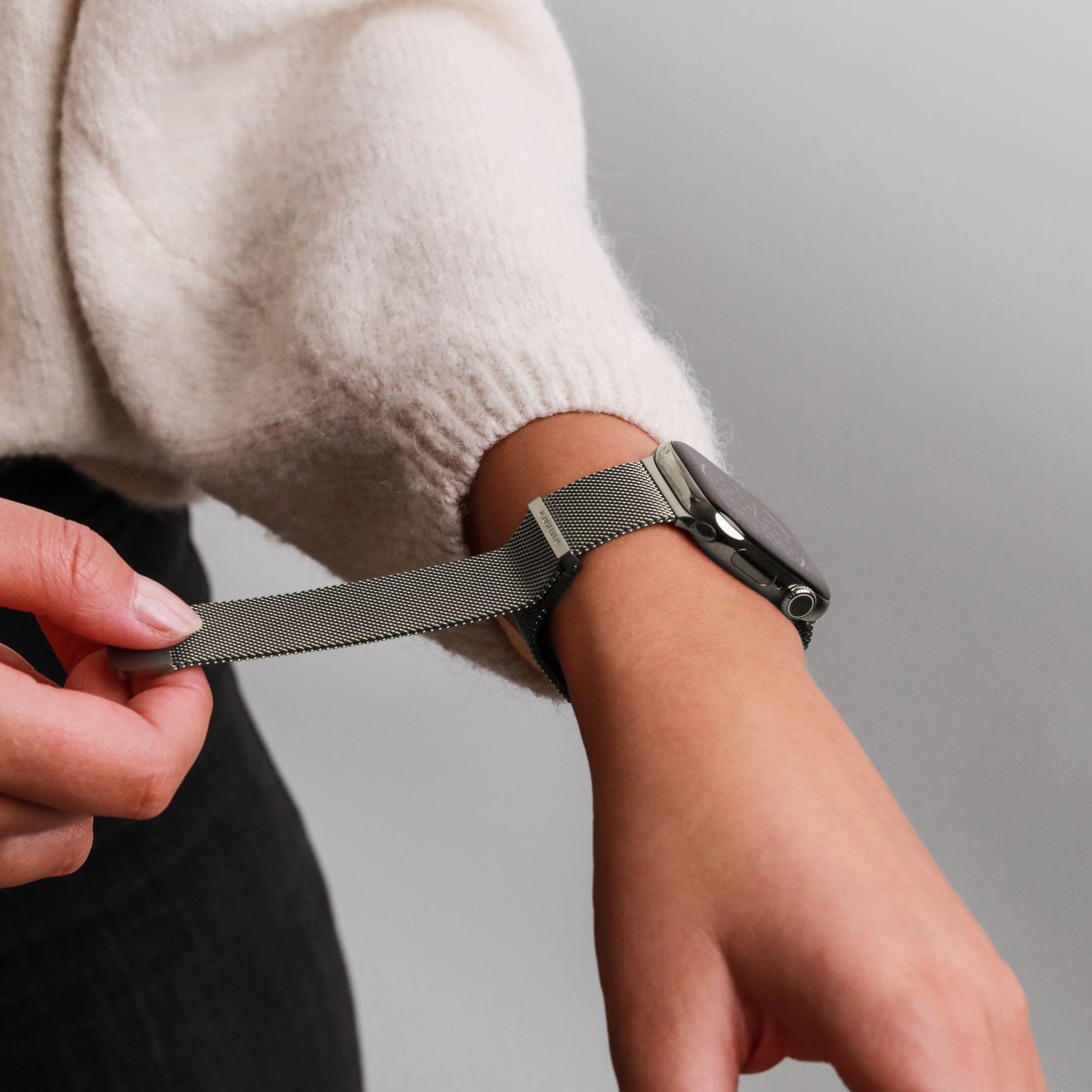 Eine Person zieht ein silbernes Uhrenarmband auf ein Handgelenk mit einer Smartwatch.