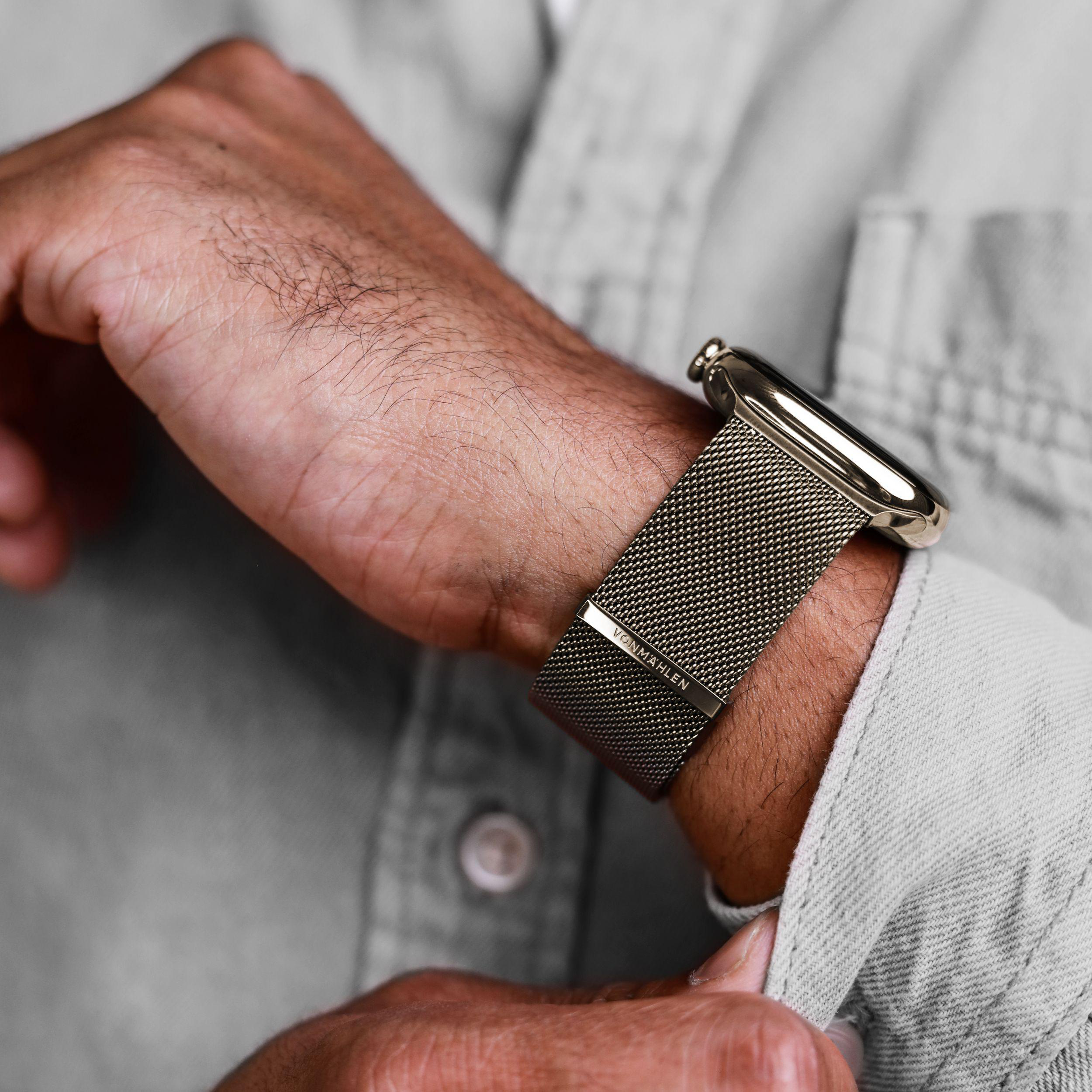 Nahaufnahme einer Hand mit einer goldenen Uhr mit Mesh-Armband.