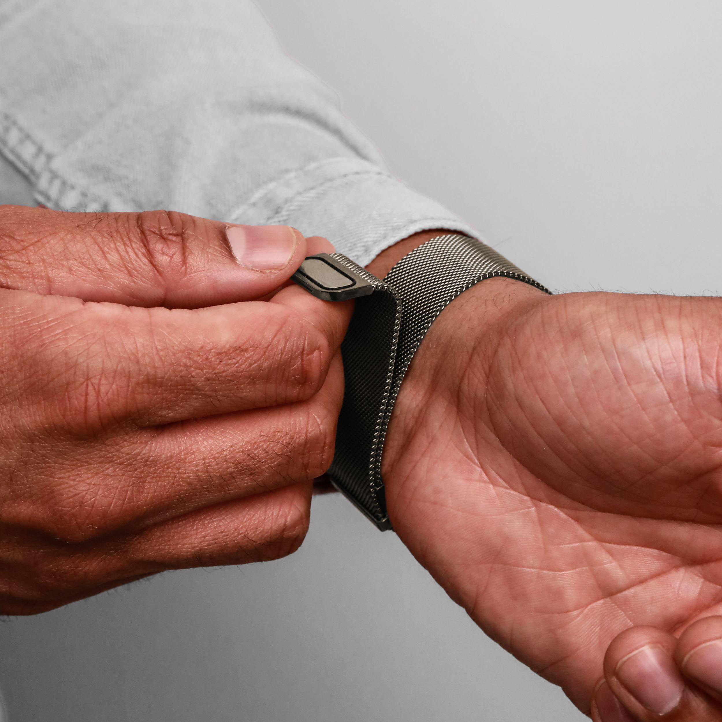 Mann schließt ein silbernes Mesh-Armband an seinem Handgelenk.