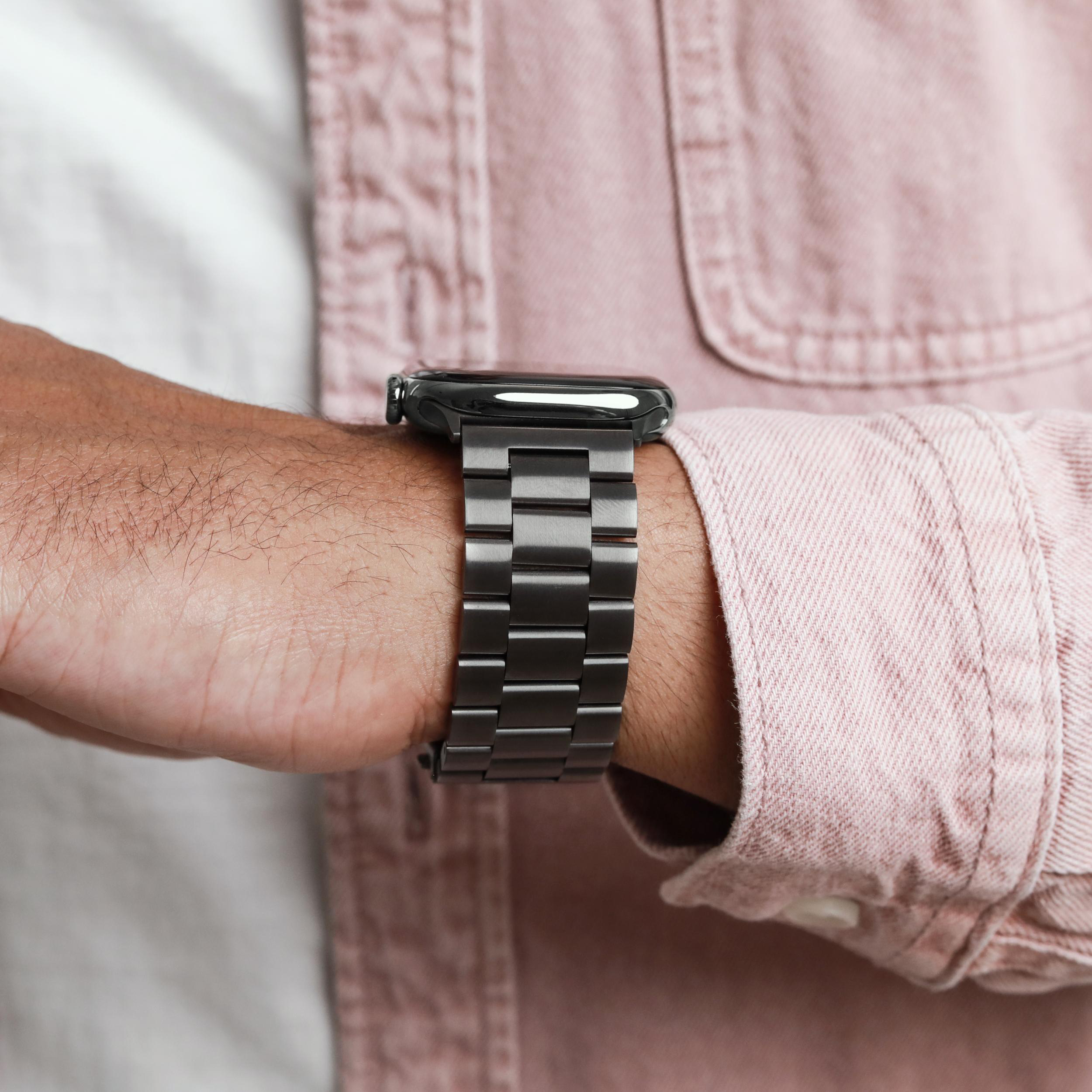 Ein Mann trägt eine graue Metalluhr mit einem Gliederarmband an seinem Handgelenk.