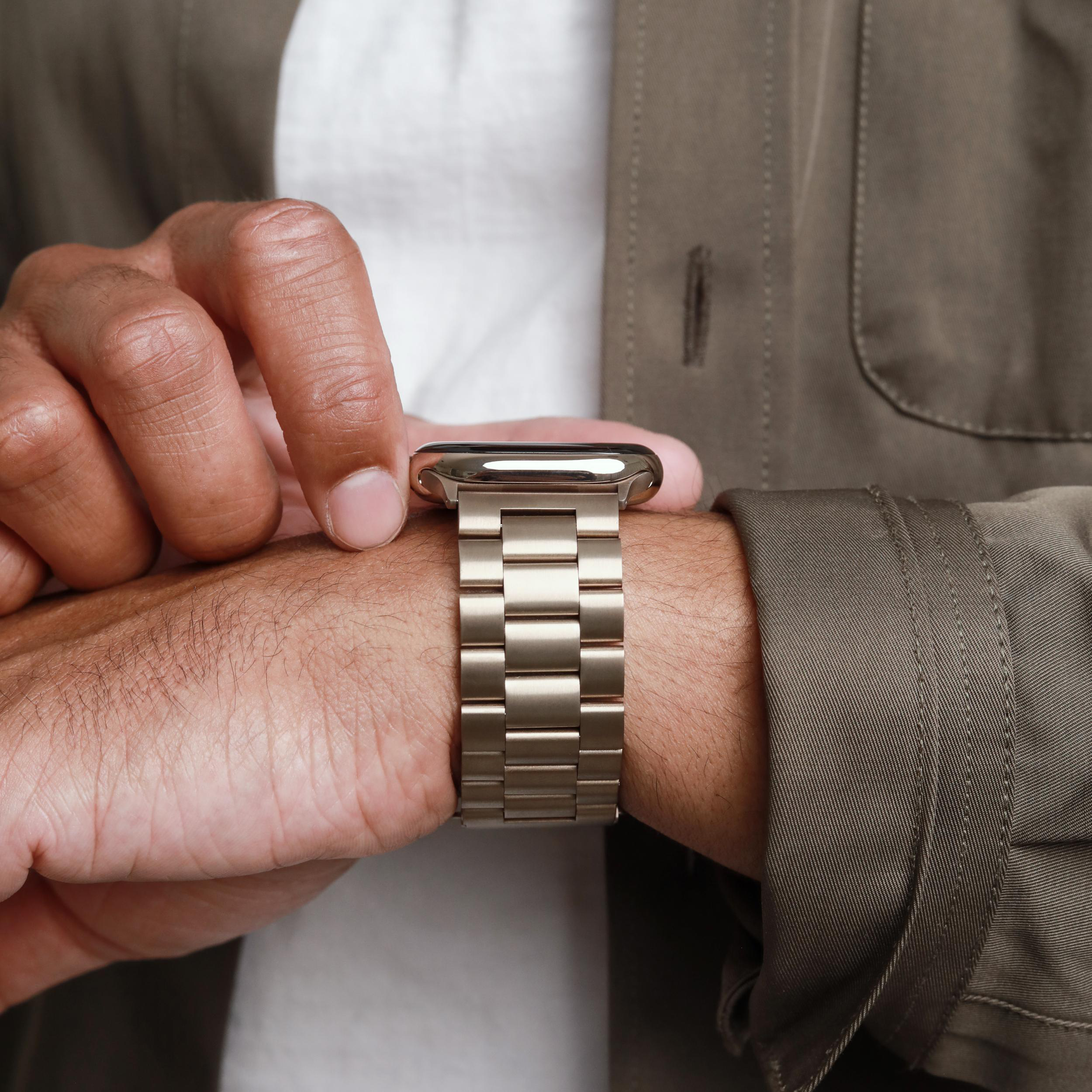 Nahaufnahme einer Hand mit einer goldenen Apple Watch mit Metallarmband.