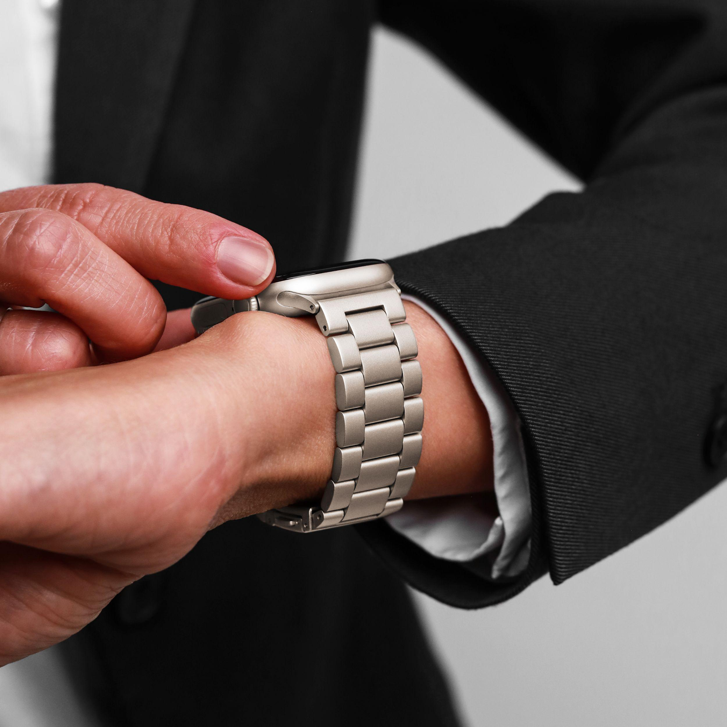 Nahaufnahme einer Hand, die eine silberne Smartwatch mit Metallarmband trägt.