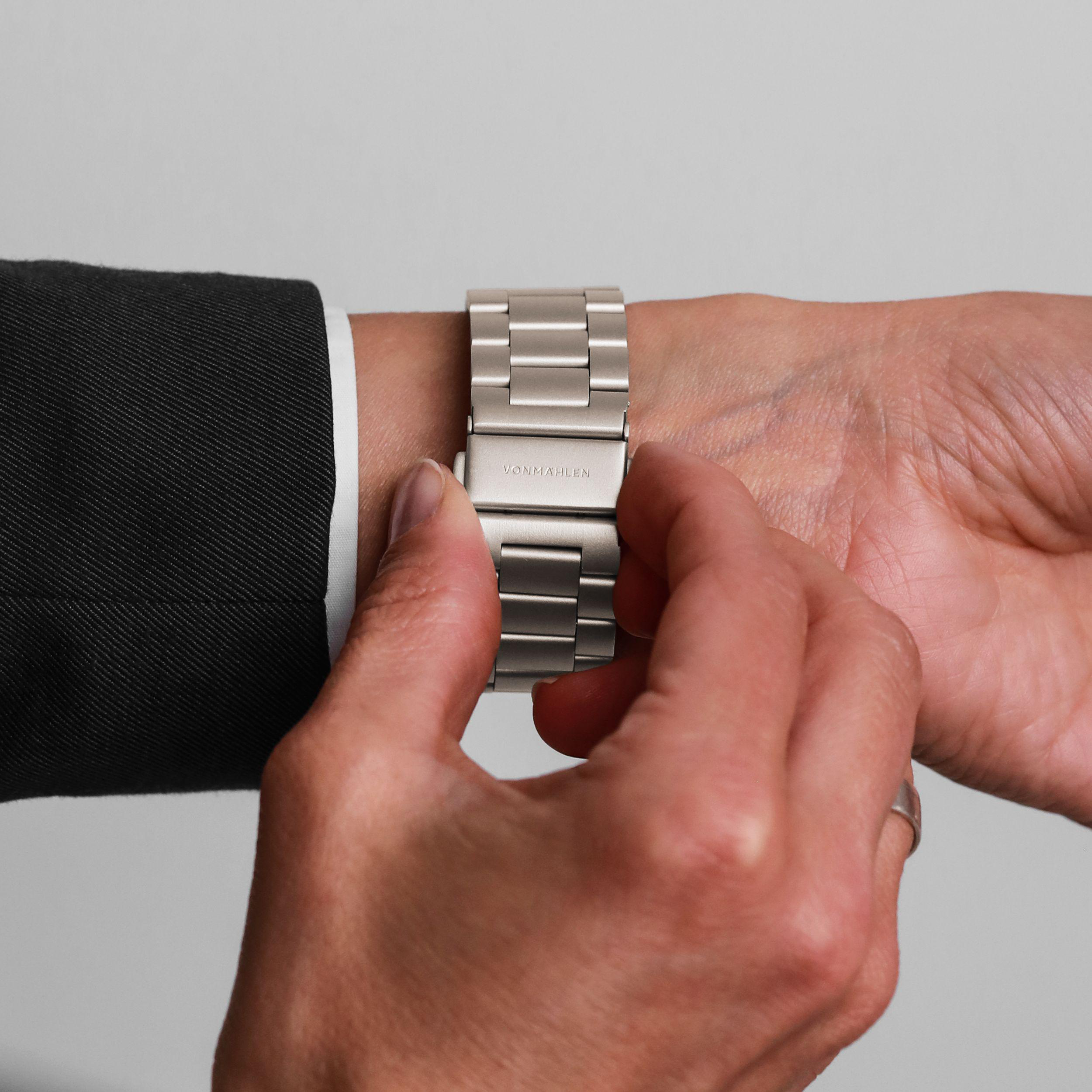 Person schließt eine silberne Armbanduhr mit dem Namen VOMMAHLEN.